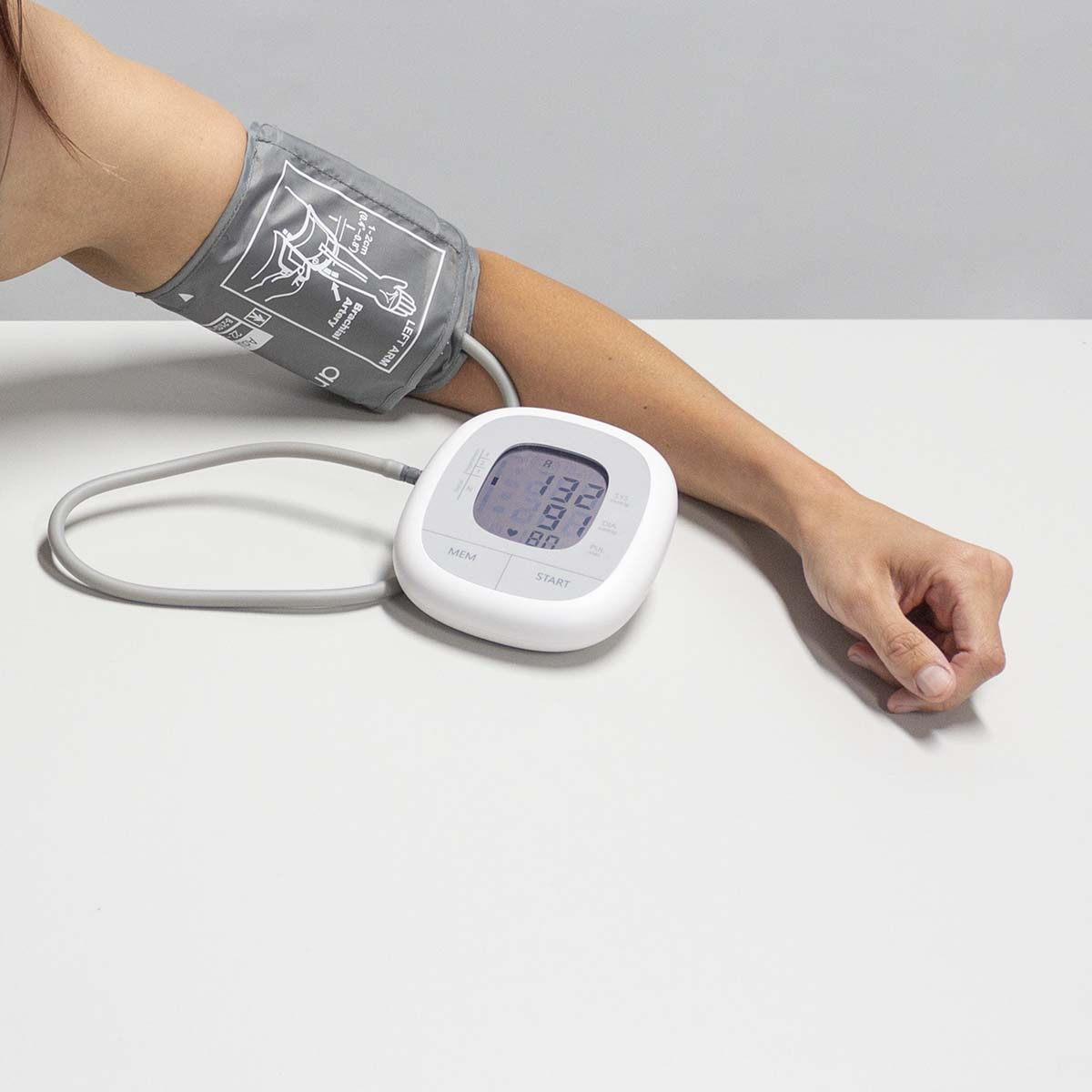 Arm einer Person mit Blutdruckmessgerät. Das Gerät ist weiß und zeigt Messwerte an.