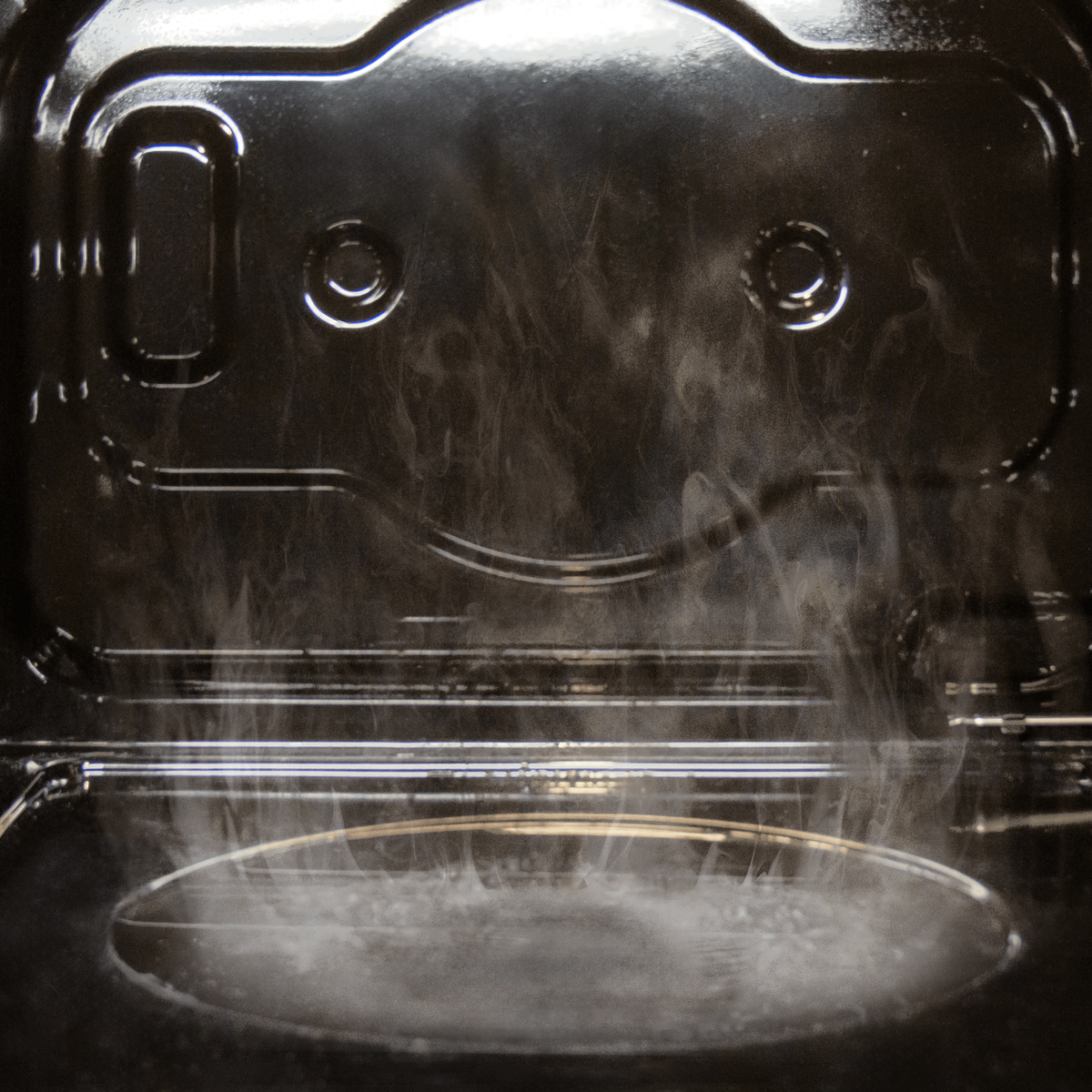 W ciemnym piekarniku para unosi się z okrągłego elementu.