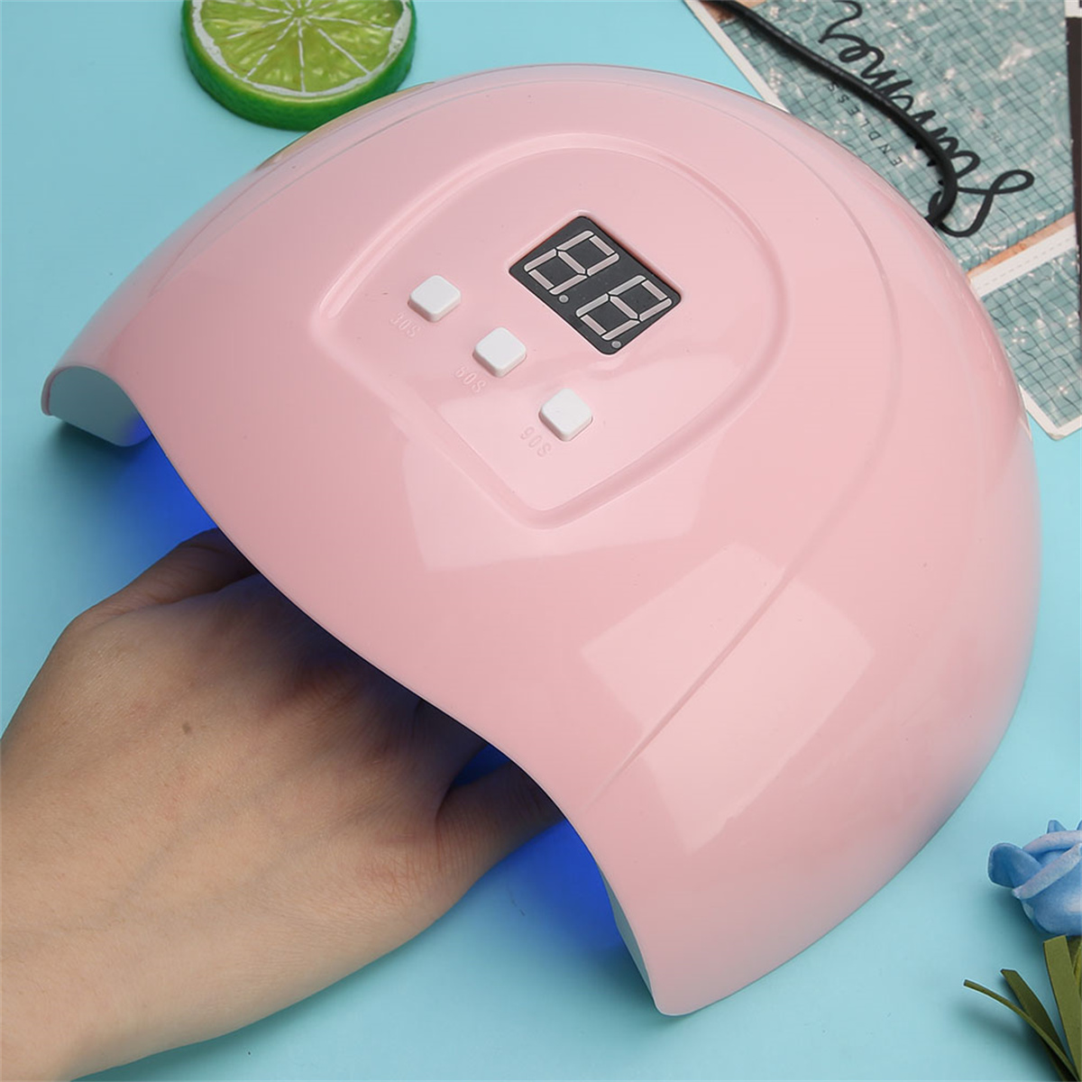 Ein pinkfarbener Nageltrockner mit Knöpfen und digitaler Anzeige, Hand innen.