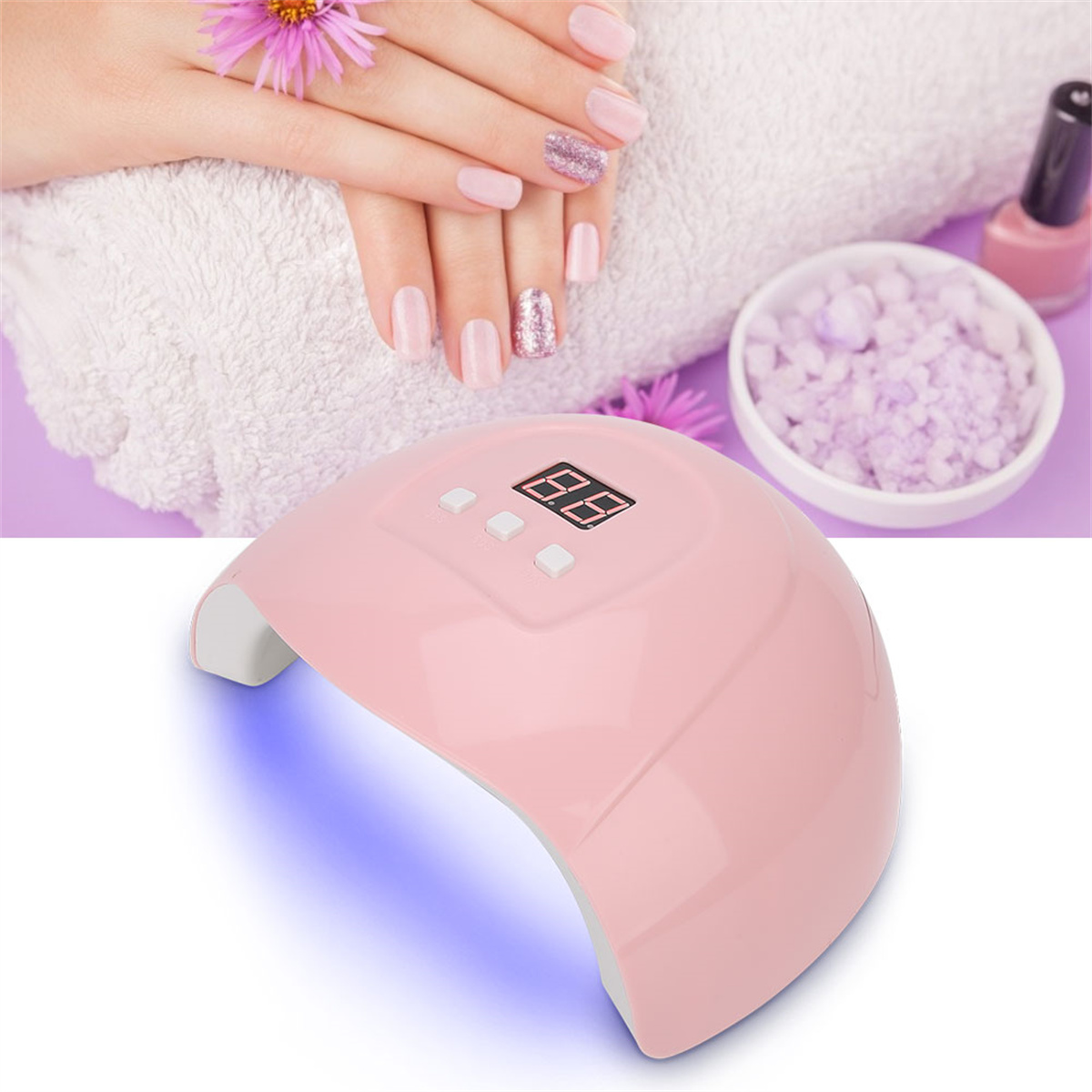 Eine rosa UV-Nagellampe mit Timer, neben einem Handtuch, Nagellack und einer Schüssel mit Badesalzen.