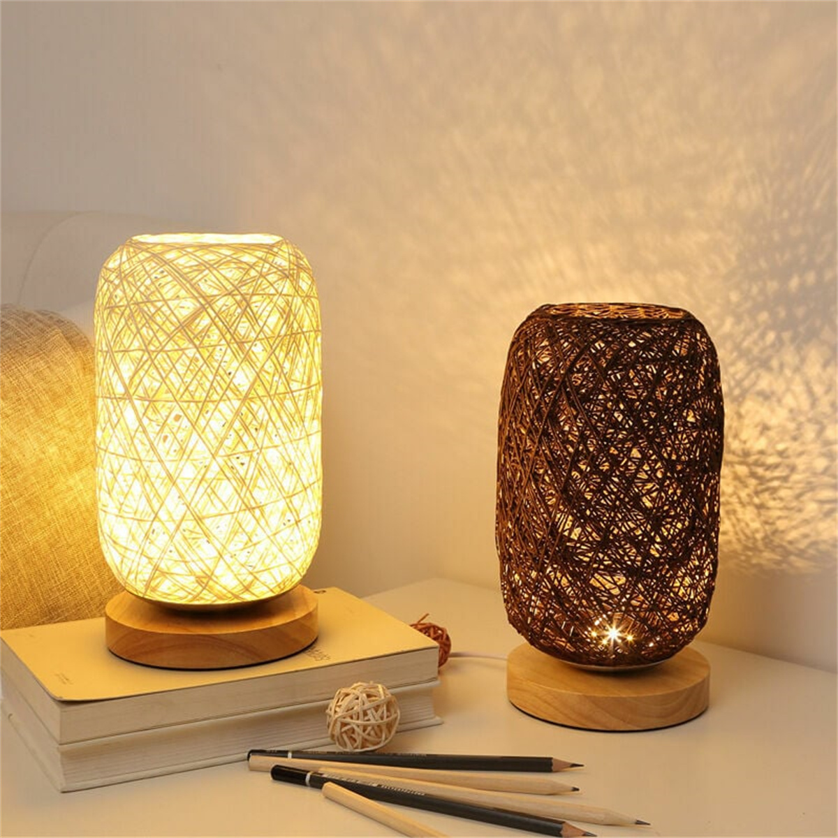 Zwei dekorative Lampen mit Glühbirnen auf einem Holztisch, Bleistifte und ein Ball daneben.