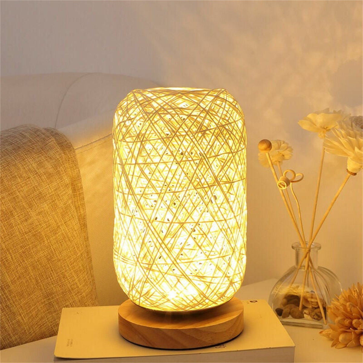 Eine dekorative Tischlampe aus gewebtem Material. Sie steht auf einem Holzsockel.