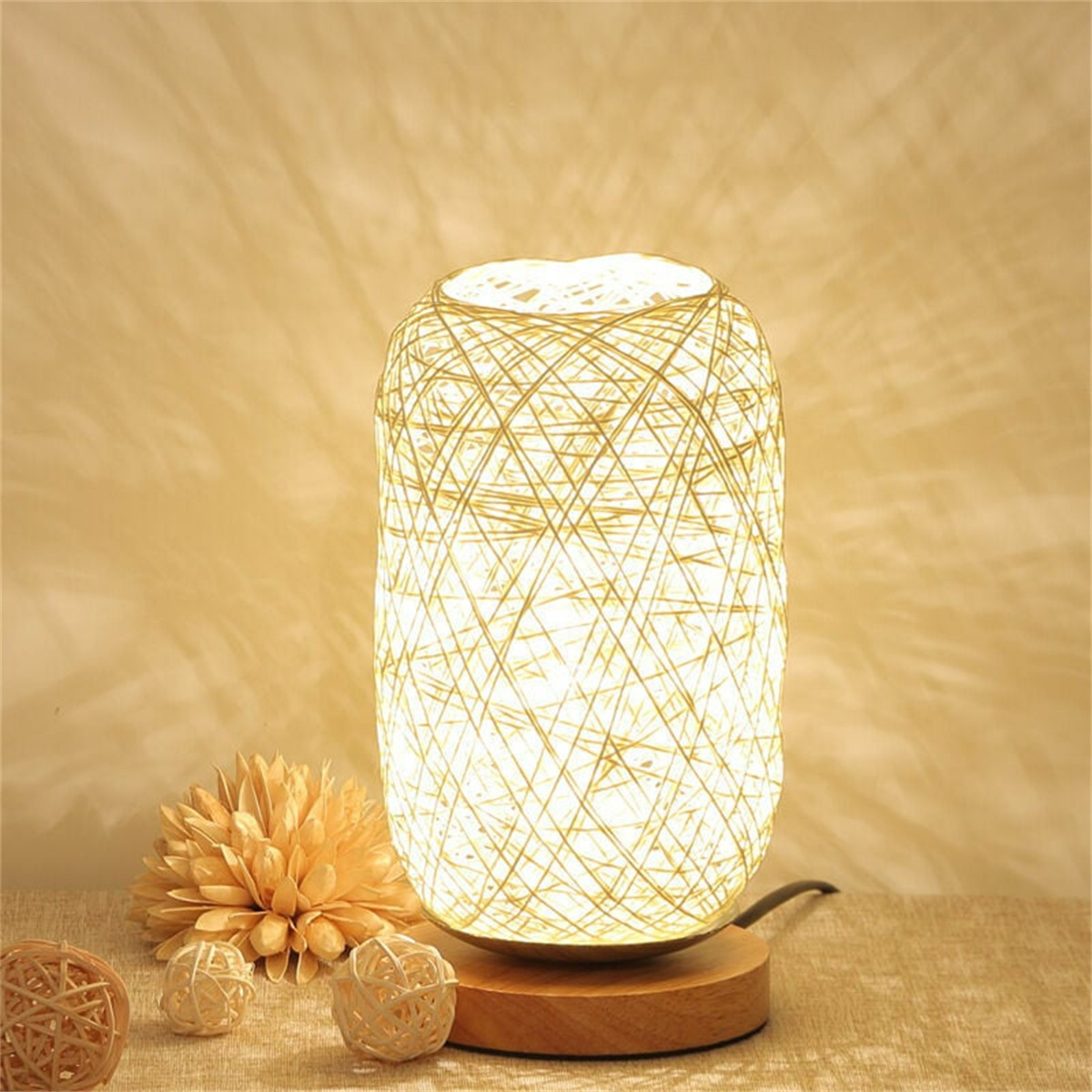 Eine Lampe aus gewebtem Stroh auf einem Holzsockel, mit dekorativen Kugeln drum herum.