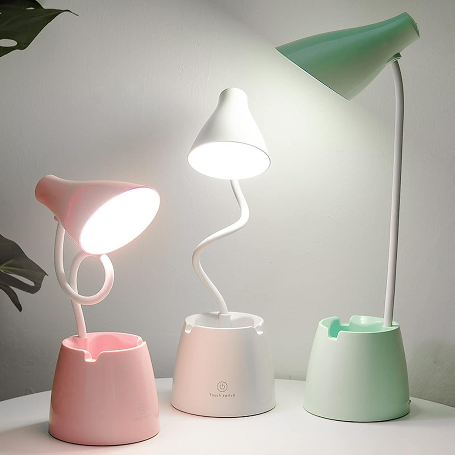 Drei Schreibtischlampen, rosa, weiß und grün, jeweils mit einzigartigem Design und Touch-Schalter.
