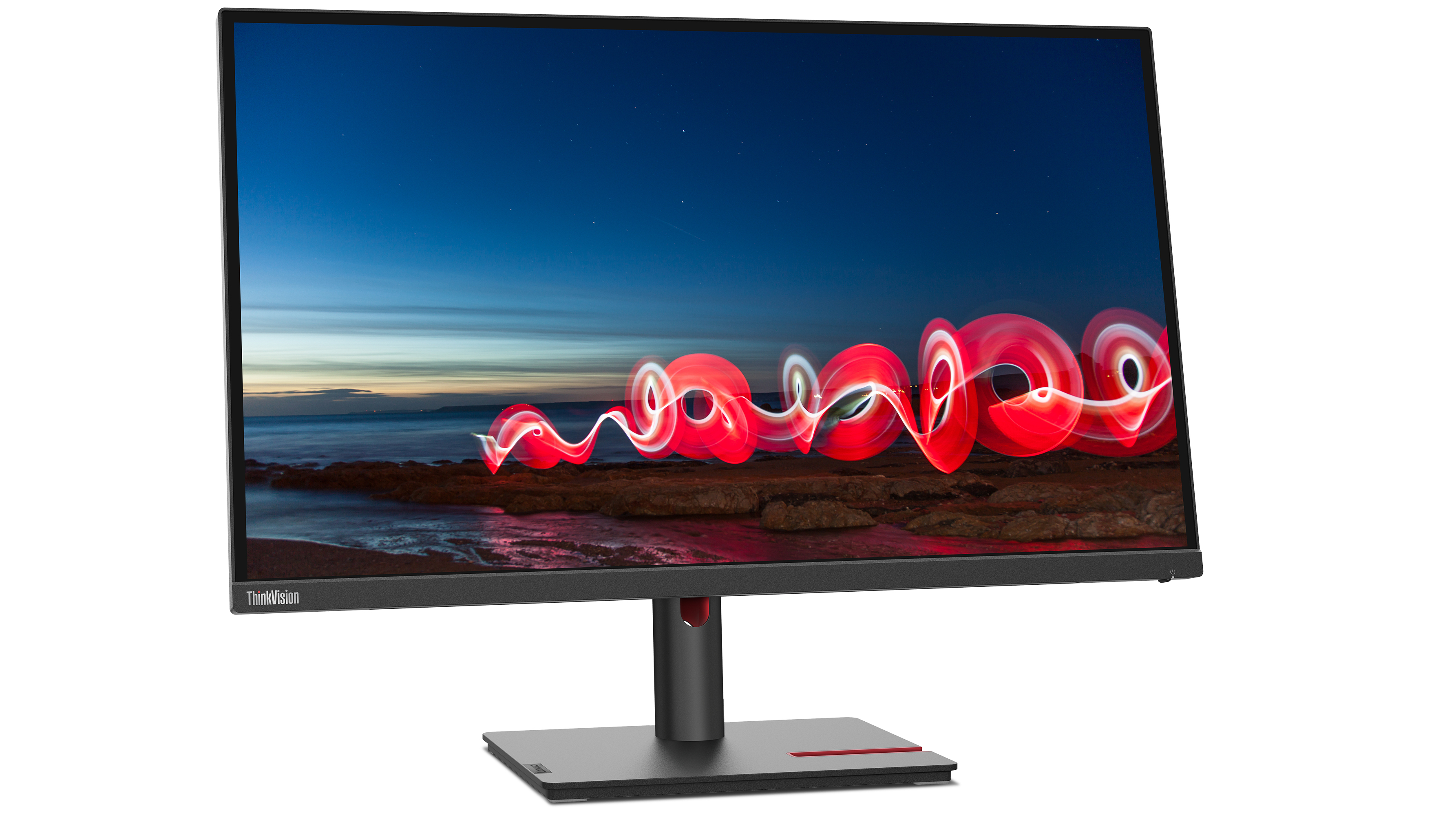 Monitor Lenovo wyświetlający nocną scenę z czerwonymi smugami światła nad ciemną linią brzegową.