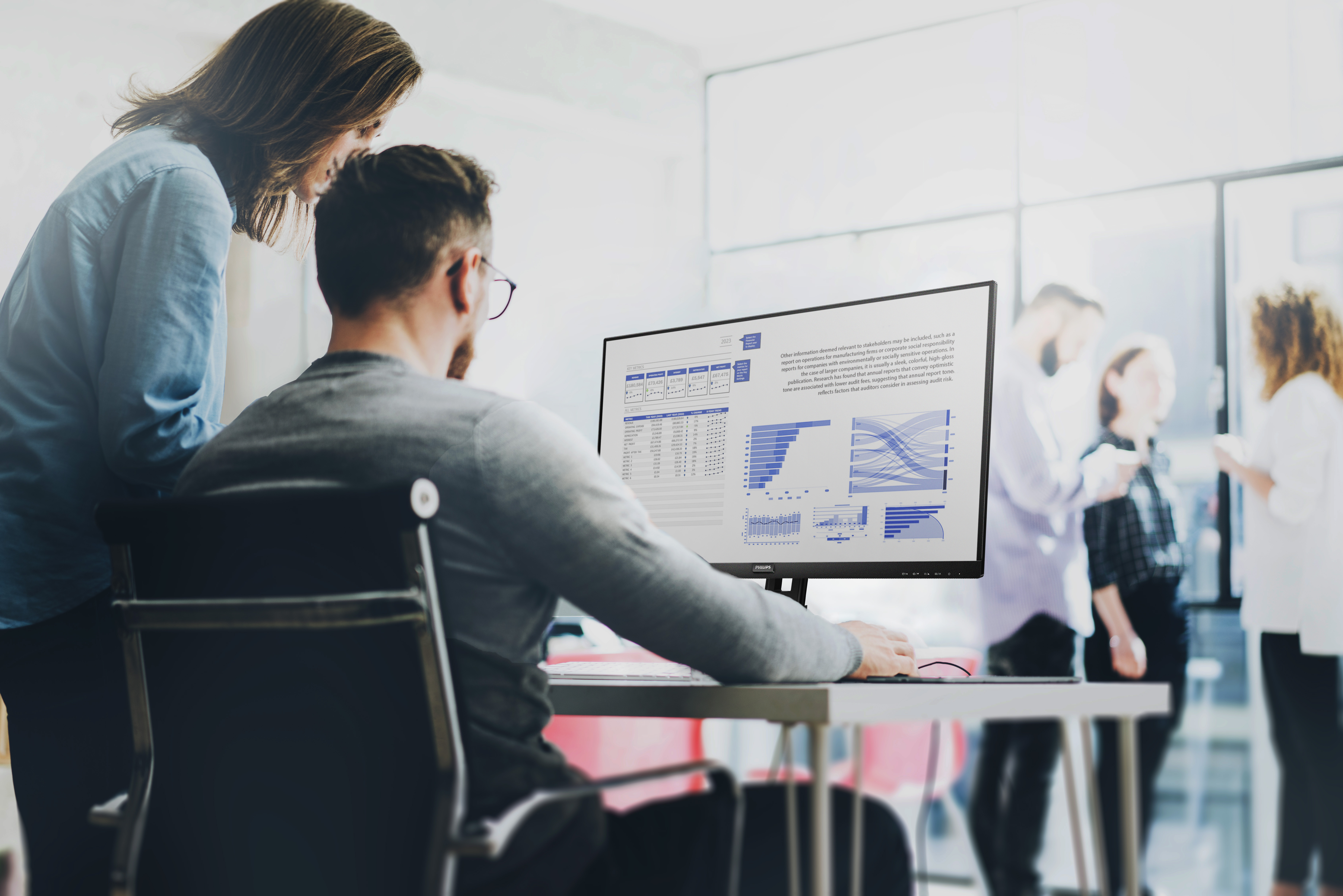 Dwie osoby patrzące na ekran komputera z wykresami i grafikami.