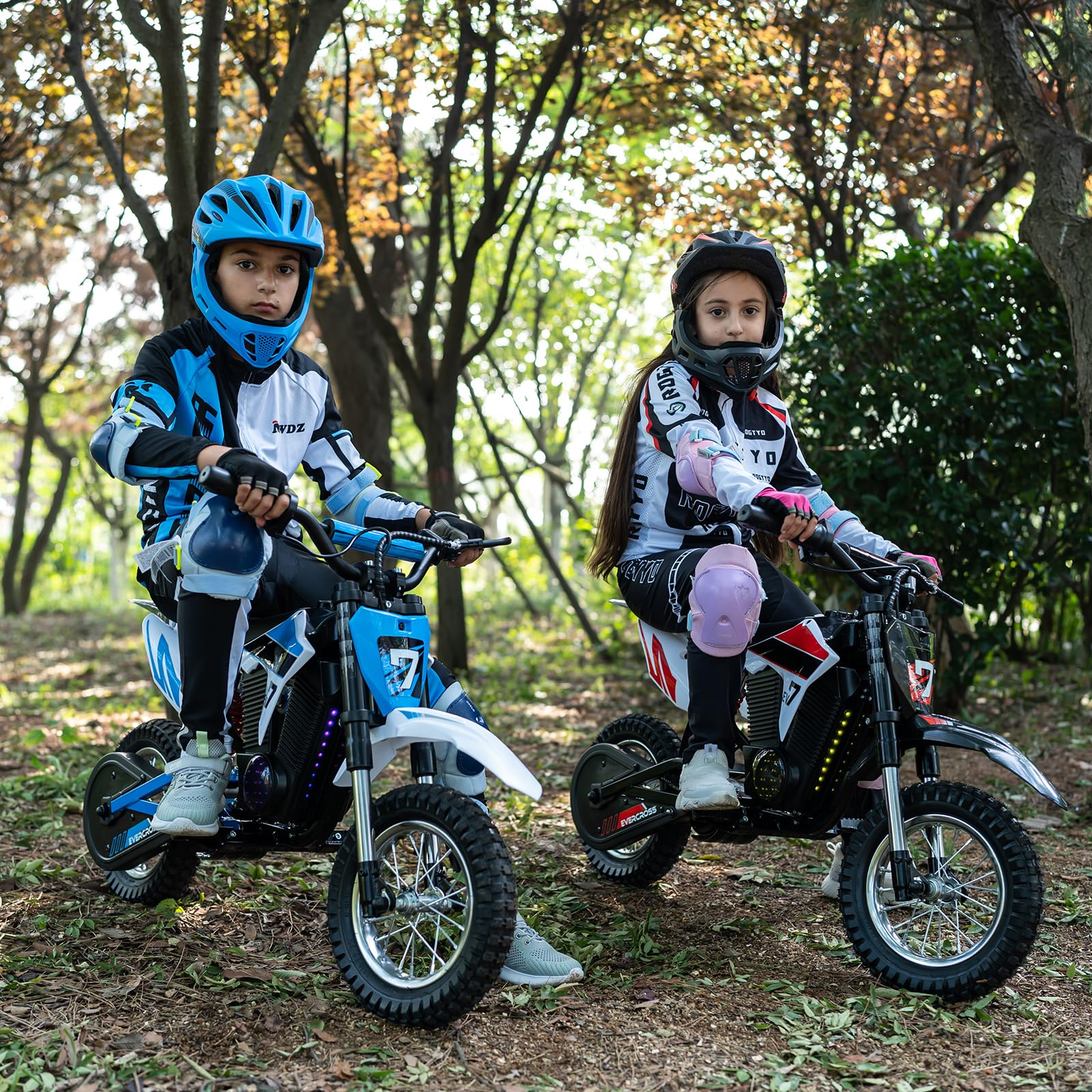 Due bambini su moto giocattolo, con caschi e protezioni, all'aperto.