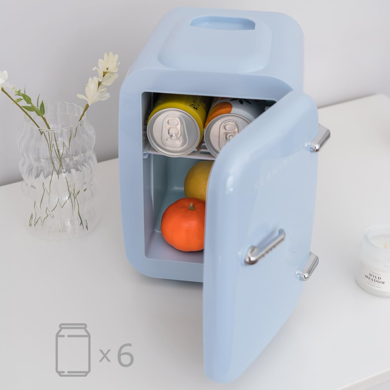 Pequeño refrigerador azul con latas y frutas adentro. Tiene una puerta abierta.