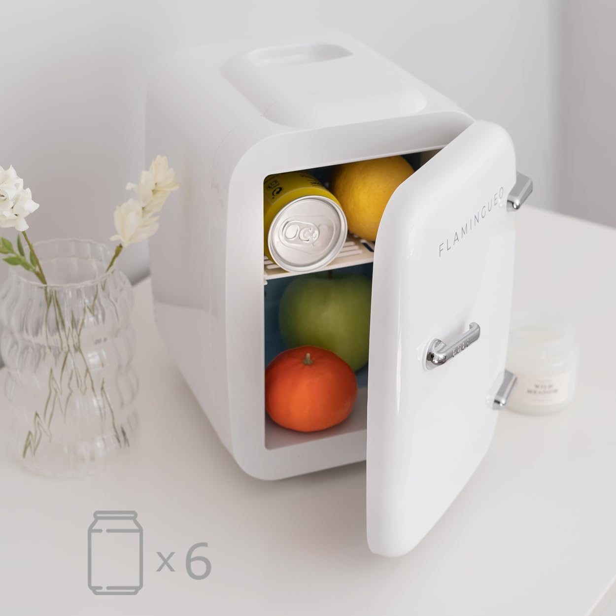 Mini nevera blanca con puerta abierta, que contiene una lata, una manzana y una naranja.