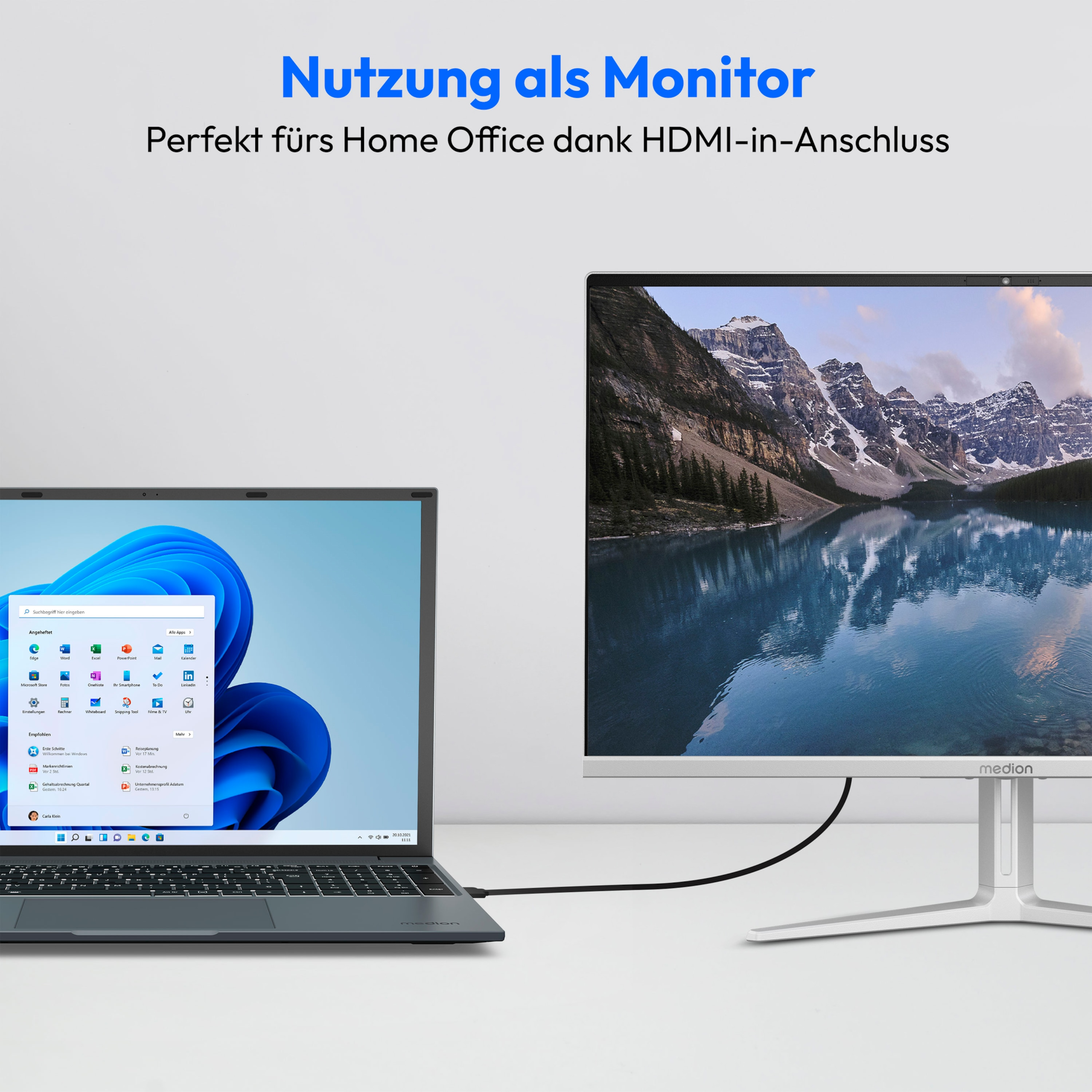 Ein Laptop, der mit einem Monitor verbunden ist. Der Monitor zeigt eine Berglandschaft, der Laptop einen Windows-Bildschirm.