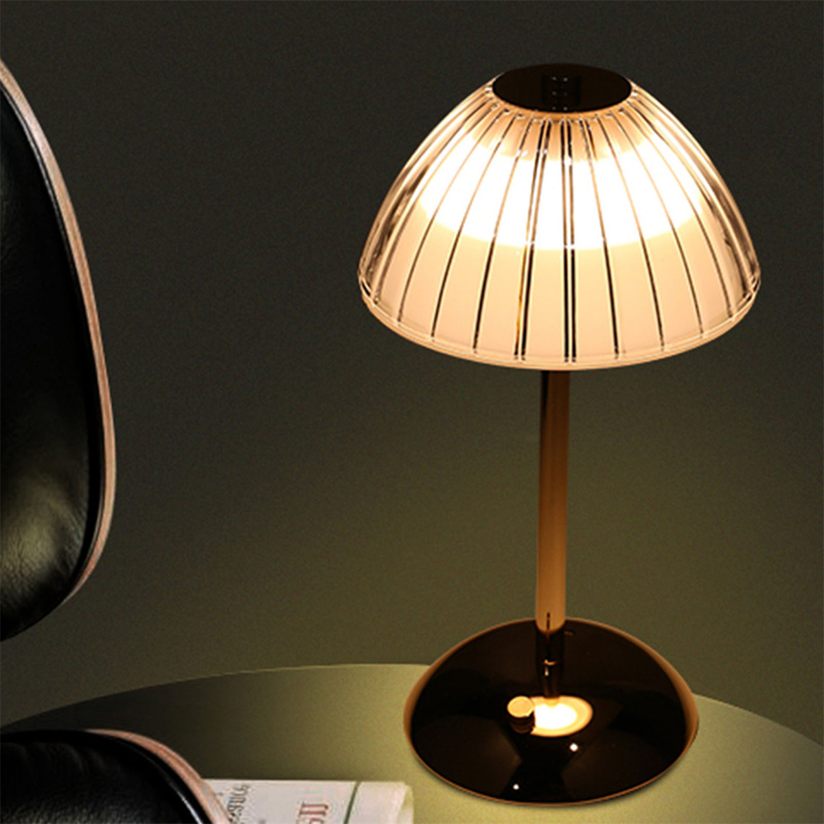 Tischlampe mit goldenem Stiel, transparentem Schirm. Dunkler Hintergrund.
