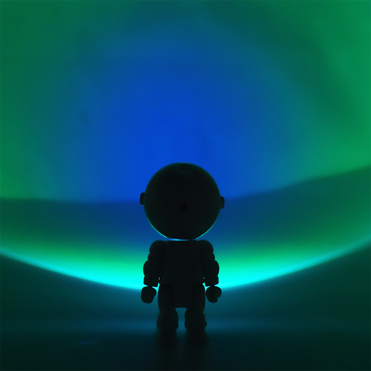 Eine Lampe in Form eines Cartoon-Roboters. Der Hintergrund ist blau und grün.