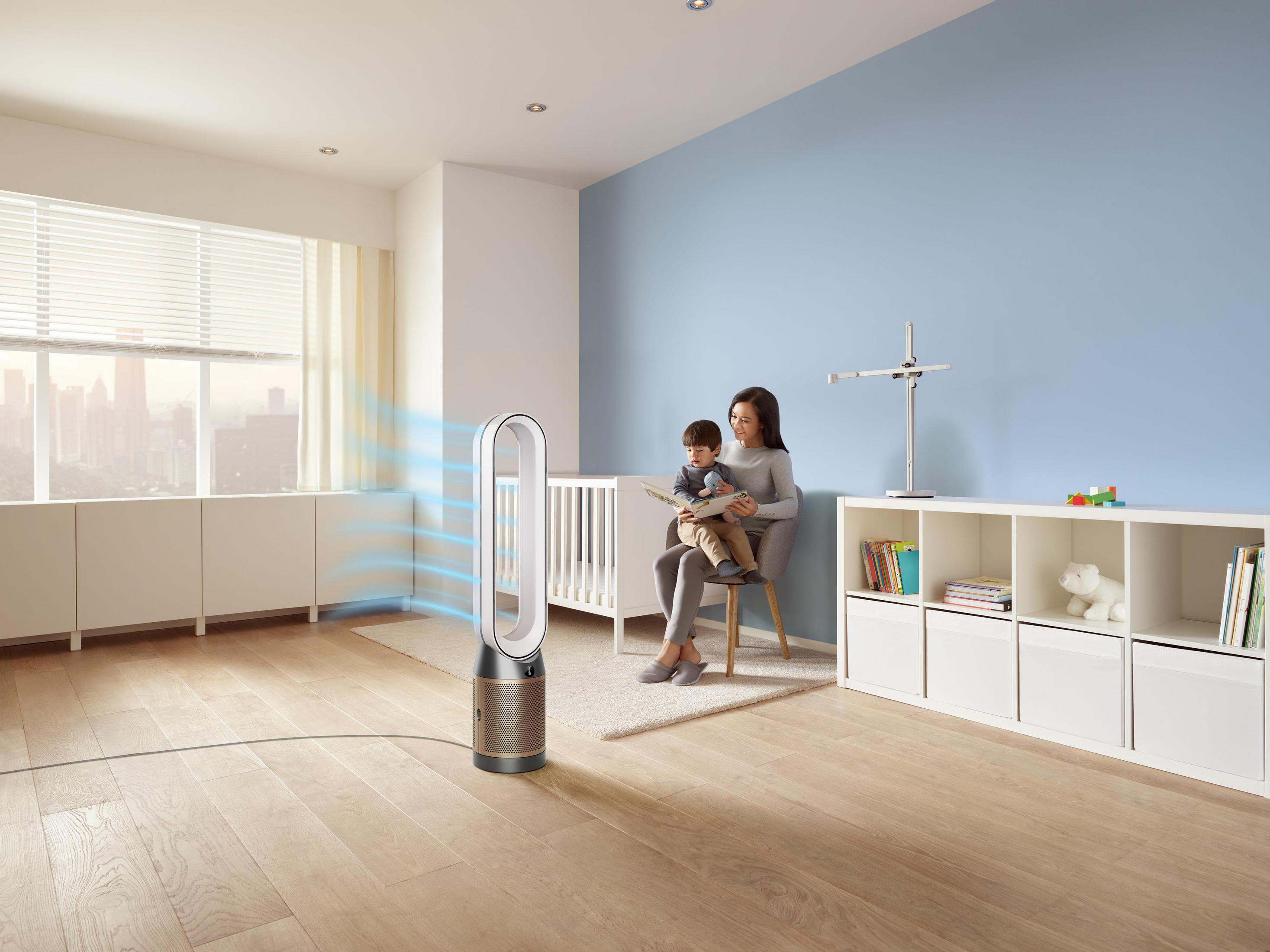 Zimmer mit Ventilator, Babybett, Frau mit Kind und blauer Wand.