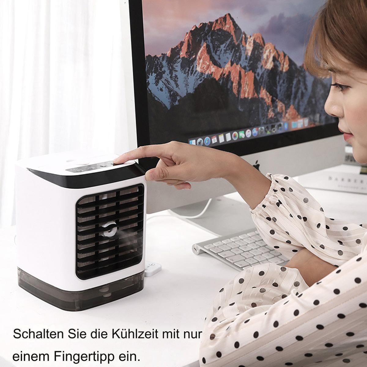 Der Finger einer Frau drückt auf einen Knopf eines weißen Luftkühlers. Im Hintergrund ist ein Berg abgebildet.