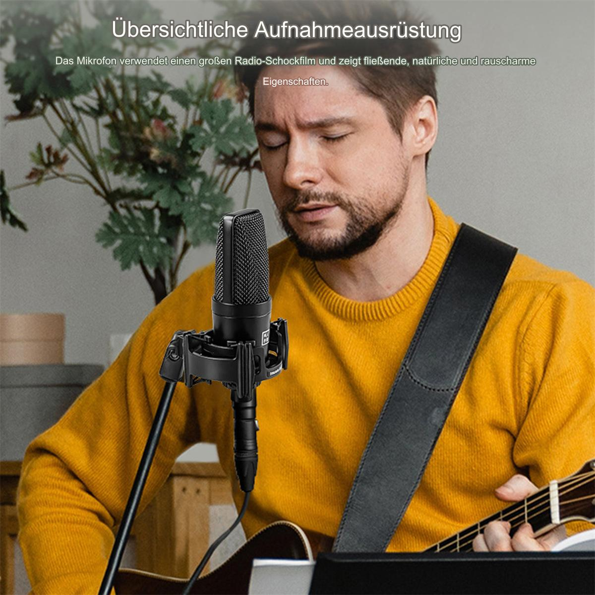 Mann spielt Gitarre, hält ein schwarzes Mikrofon, trägt einen gelben Pullover. Ein Mikrofonständer ist vorhanden.
