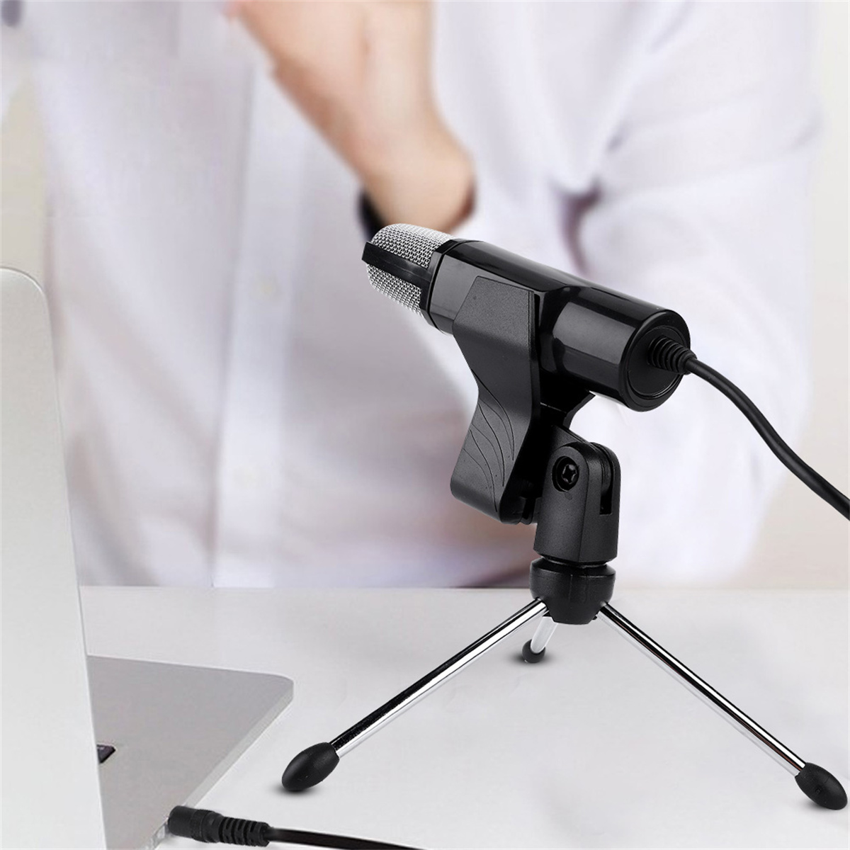 Ein schwarzes Mikrofon auf einem Stativ, über ein Kabel mit einem Laptop verbunden. Der Hintergrund ist unscharf.