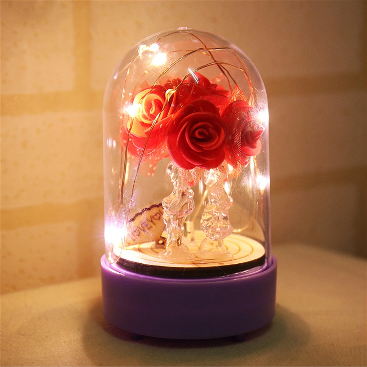 Glaskuppel mit roten Rosen und Lichtern auf Holzsockel. Dekorativ, warmes Licht.