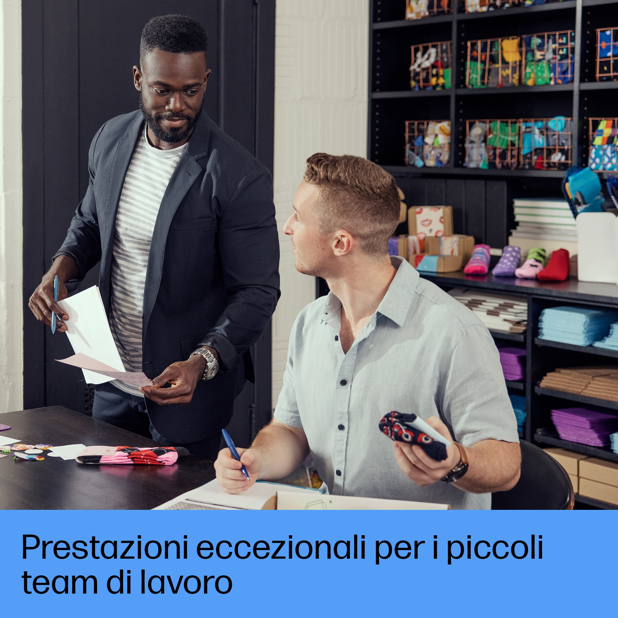 Dwóch mężczyzn w biurze omawia dokumenty. Jeden w garniturze, drugi trzyma zabawkę.