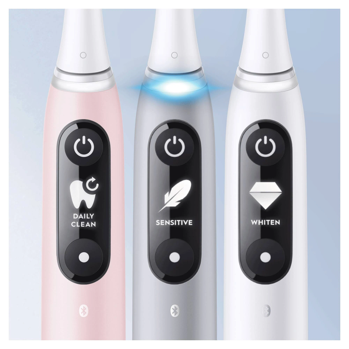 Tres cepillos de dientes eléctricos, rosa, plateado y blanco, cada uno con un modo diferente iluminado.