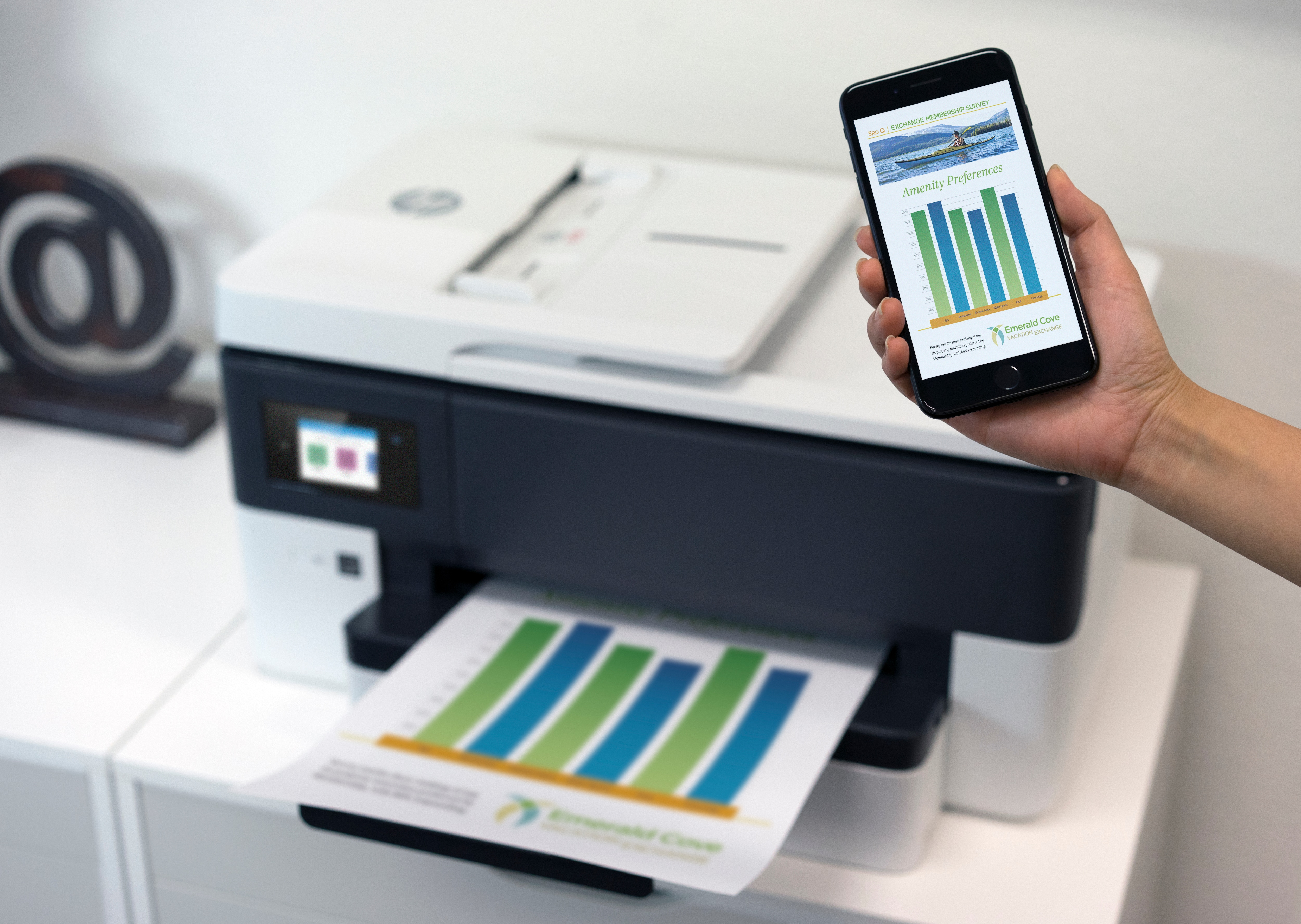 Ein Drucker druckt ein Diagramm, und eine Hand hält ein Telefon mit demselben Diagramm.