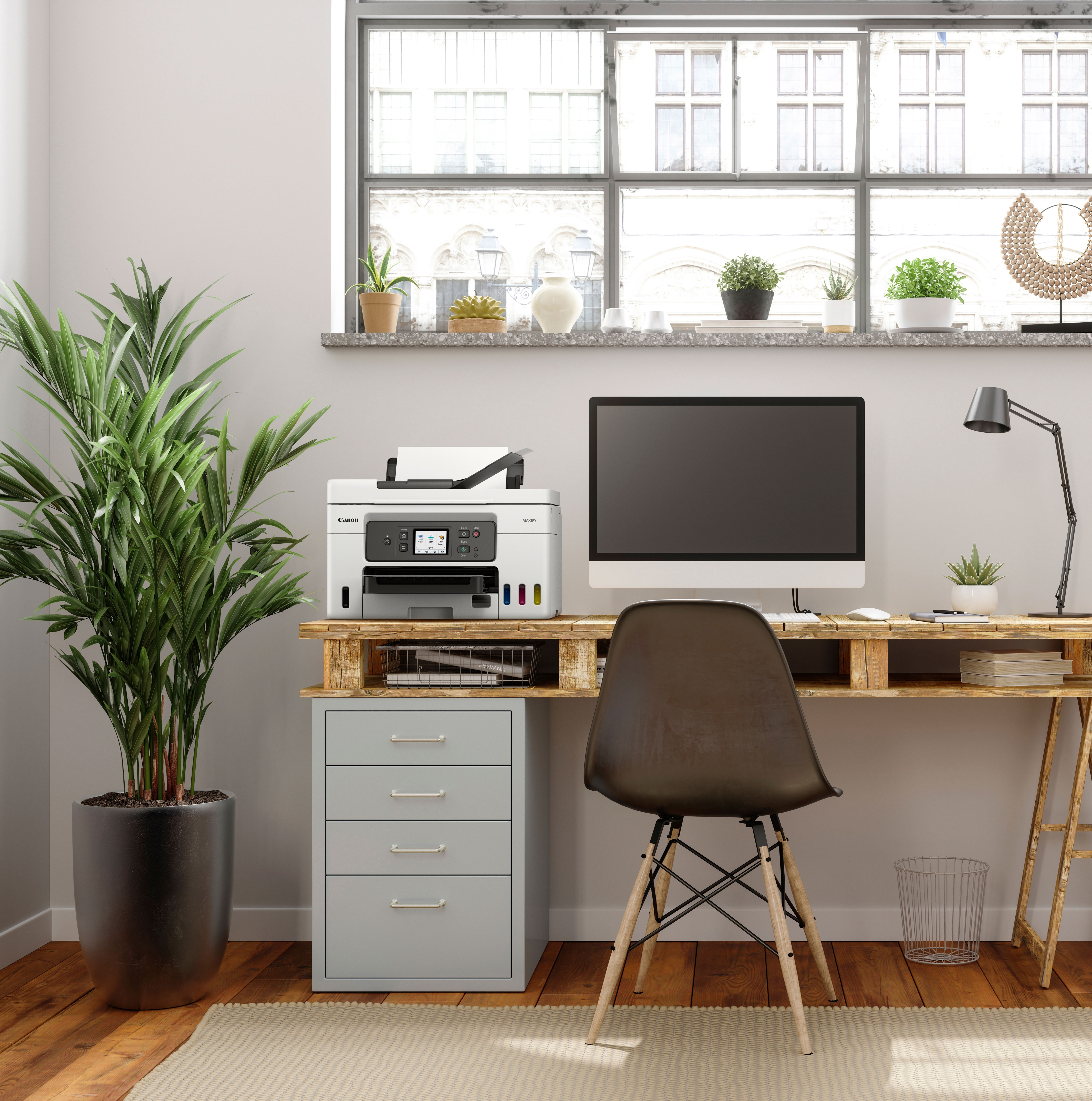 Ustawienie biurowe z drukarką na biurku, rośliną i oknem.