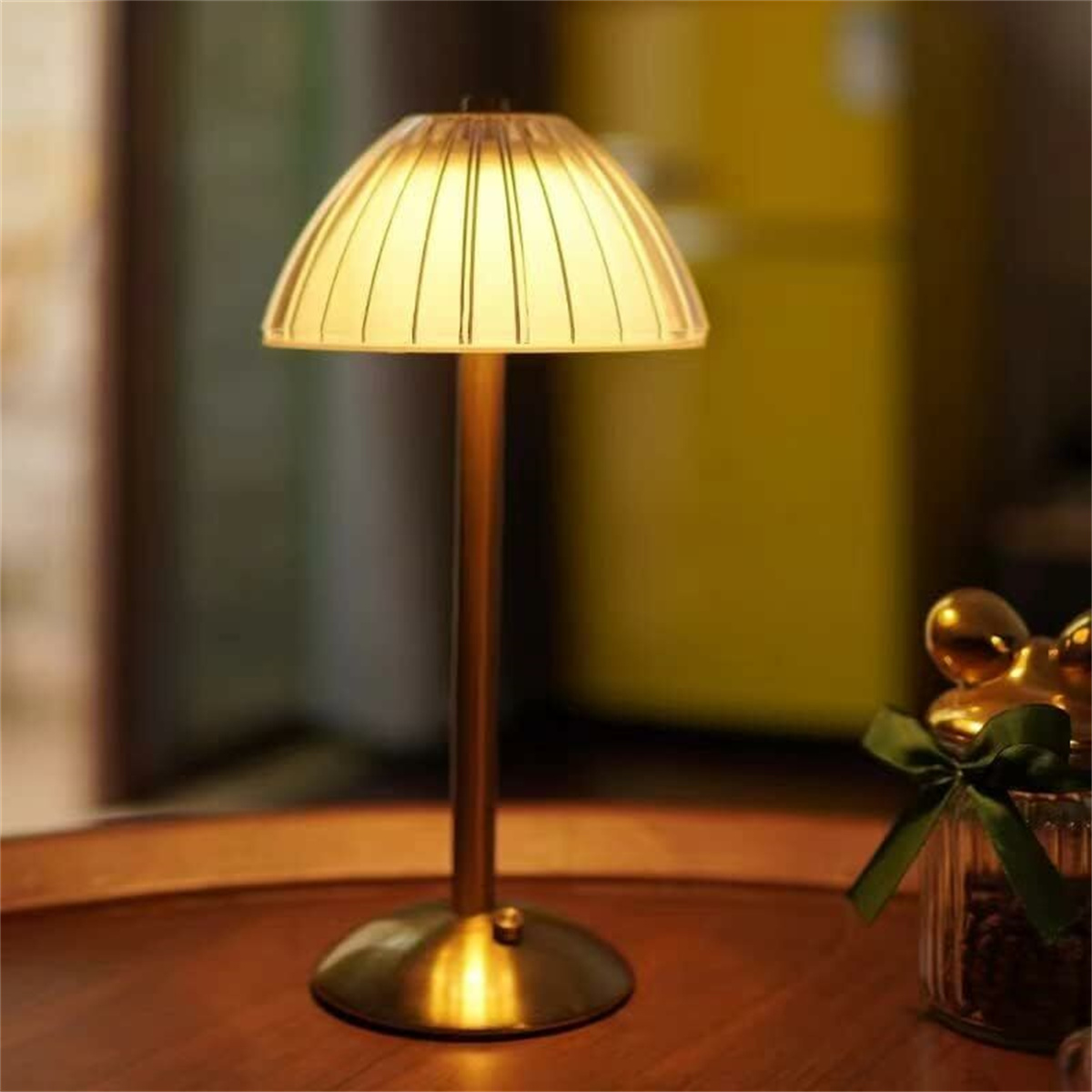 Eine goldene Tischlampe mit pilzförmigem Schirm auf einer Holzoberfläche.