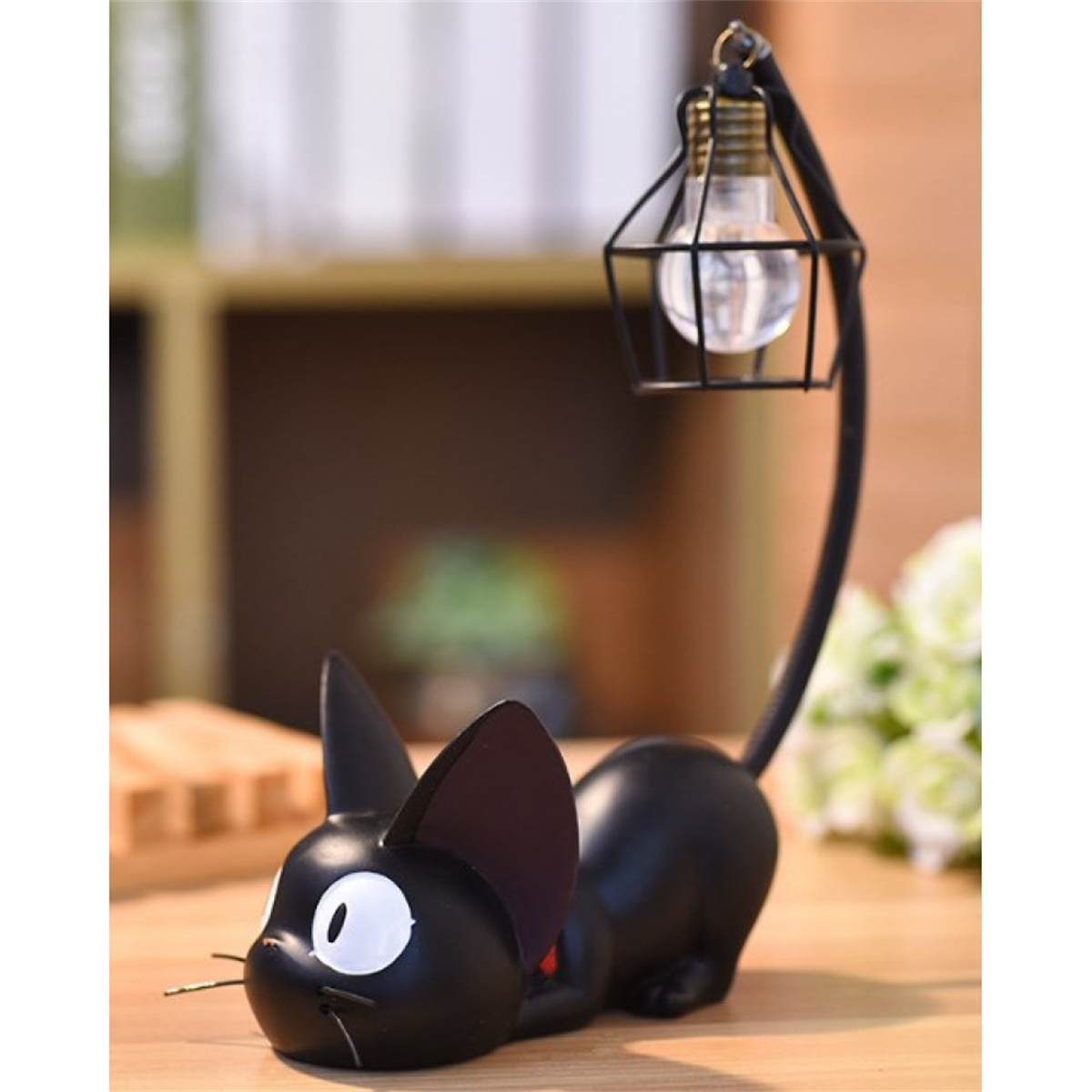 Eine schwarze katzenförmige Lampe mit einer Glühbirne in einem Käfig. Weißer Hintergrund.
