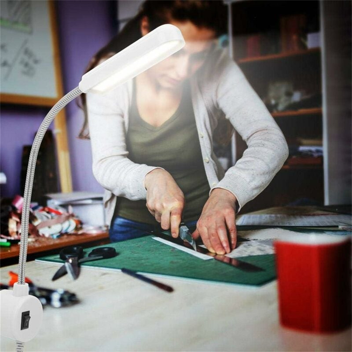 Frau schneidet mit Schere und Lineal. Eine Schreibtischlampe beleuchtet die Szene.