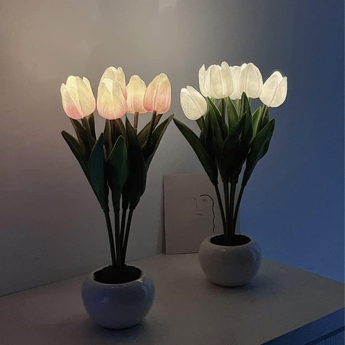 Zwei künstliche Tulpenarrangements. Die Tulpen sind weiß und rosa. Es gibt Licht und einen weißen Hintergrund.