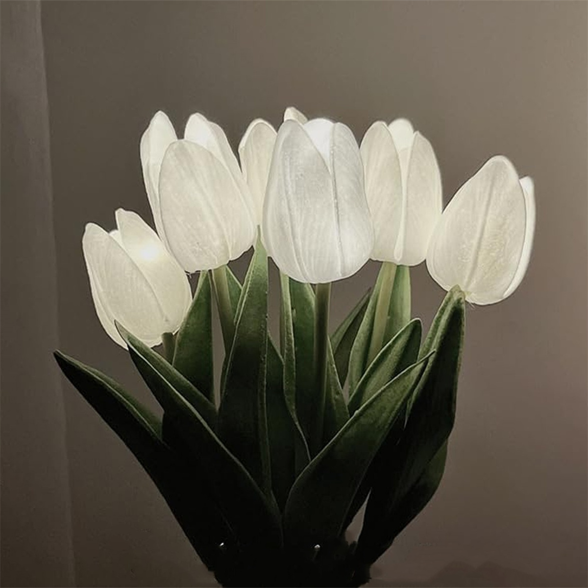 Ein Strauß weißer LED-Tulpen vor dunklem Hintergrund. Die Blütenblätter sind beleuchtet.