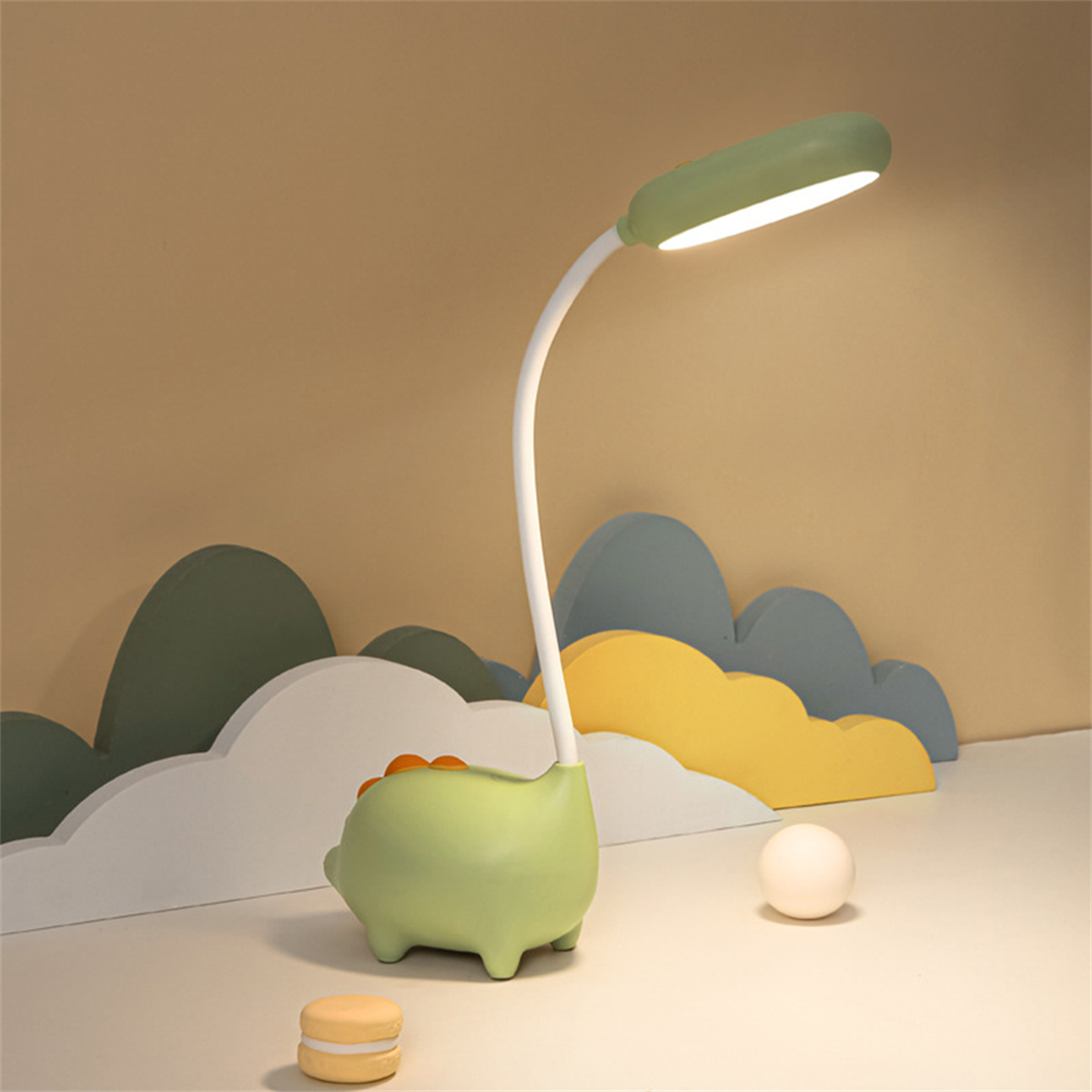 Eine grüne, dinosaurierförmige Schreibtischlampe mit hellem Licht. Sie steht auf einem Schreibtisch.