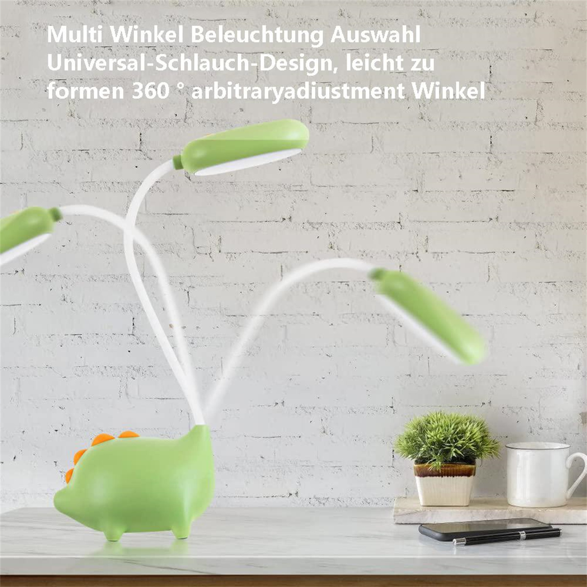Eine grüne Dinosaurierlampe mit weißem, flexiblem Arm und drei grünen Leuchtköpfen. Tasse und Stift auf dem Tisch.
