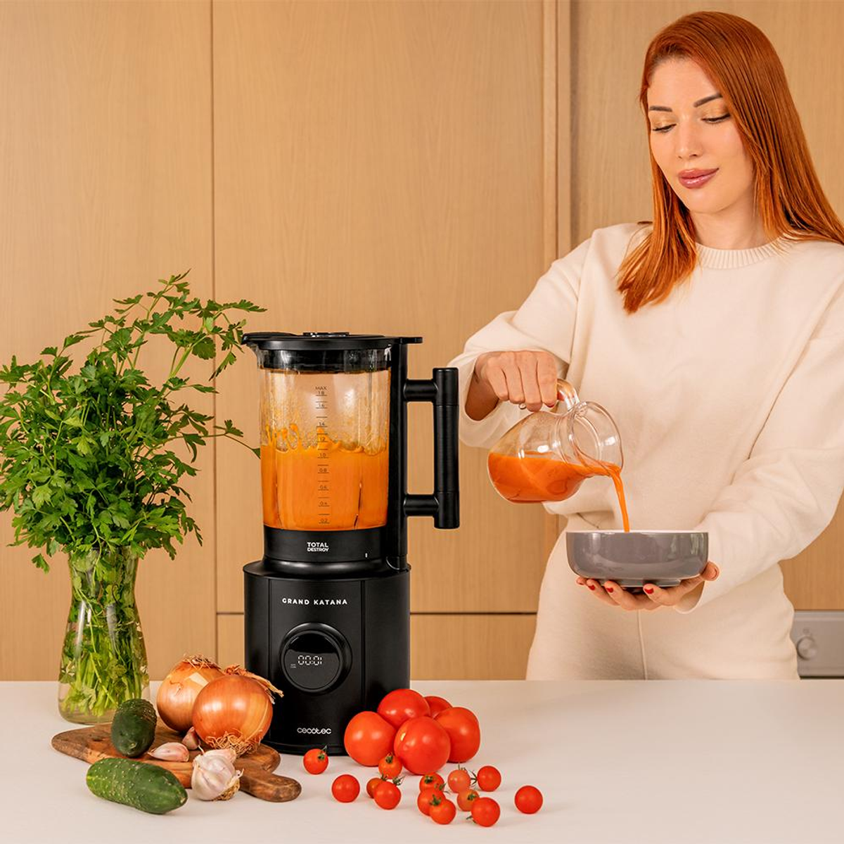 Frau gießt Suppe in Schüssel. Mixer, Gemüse und Küchentheke sichtbar.