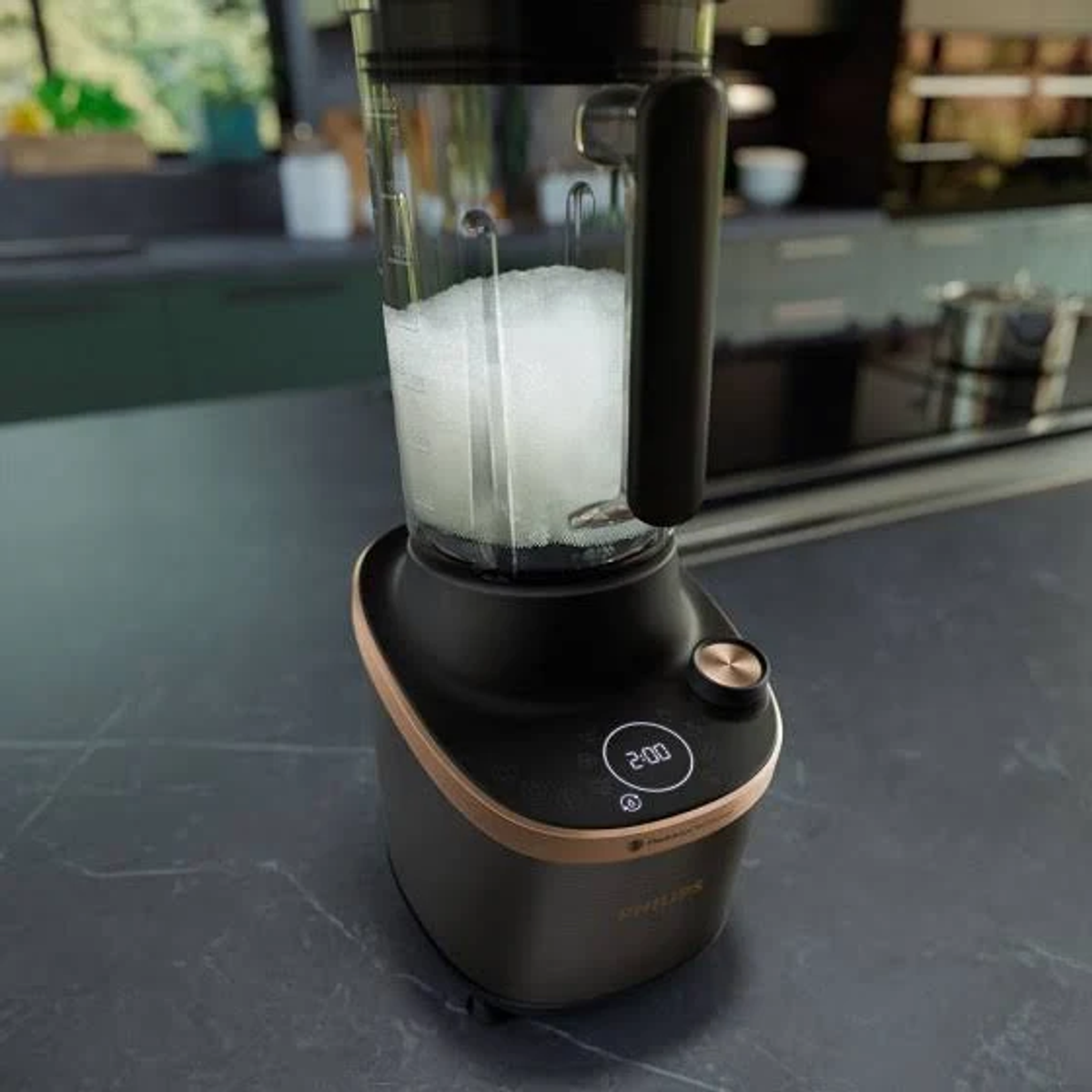 Czarny i złoty blender na blacie. Blender jest wypełniony białą cieczą i pokazuje minutnik ustawiony na 2:00.