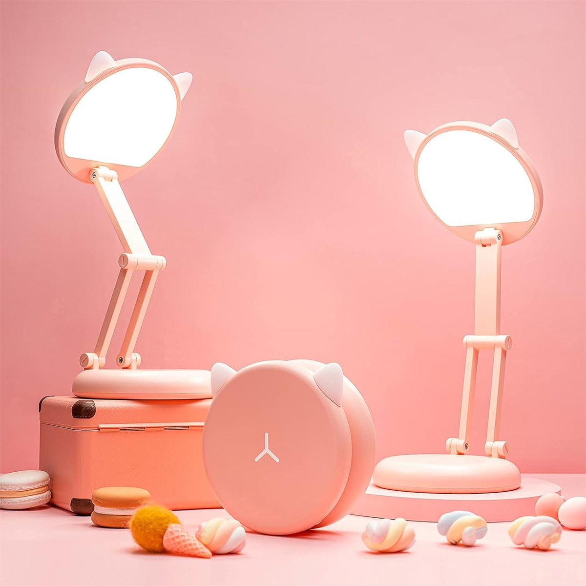 Zwei rosa Katzenohrlampen und eine rosa Box. Die Szene hat rosa, orange und blaue Süßigkeiten.