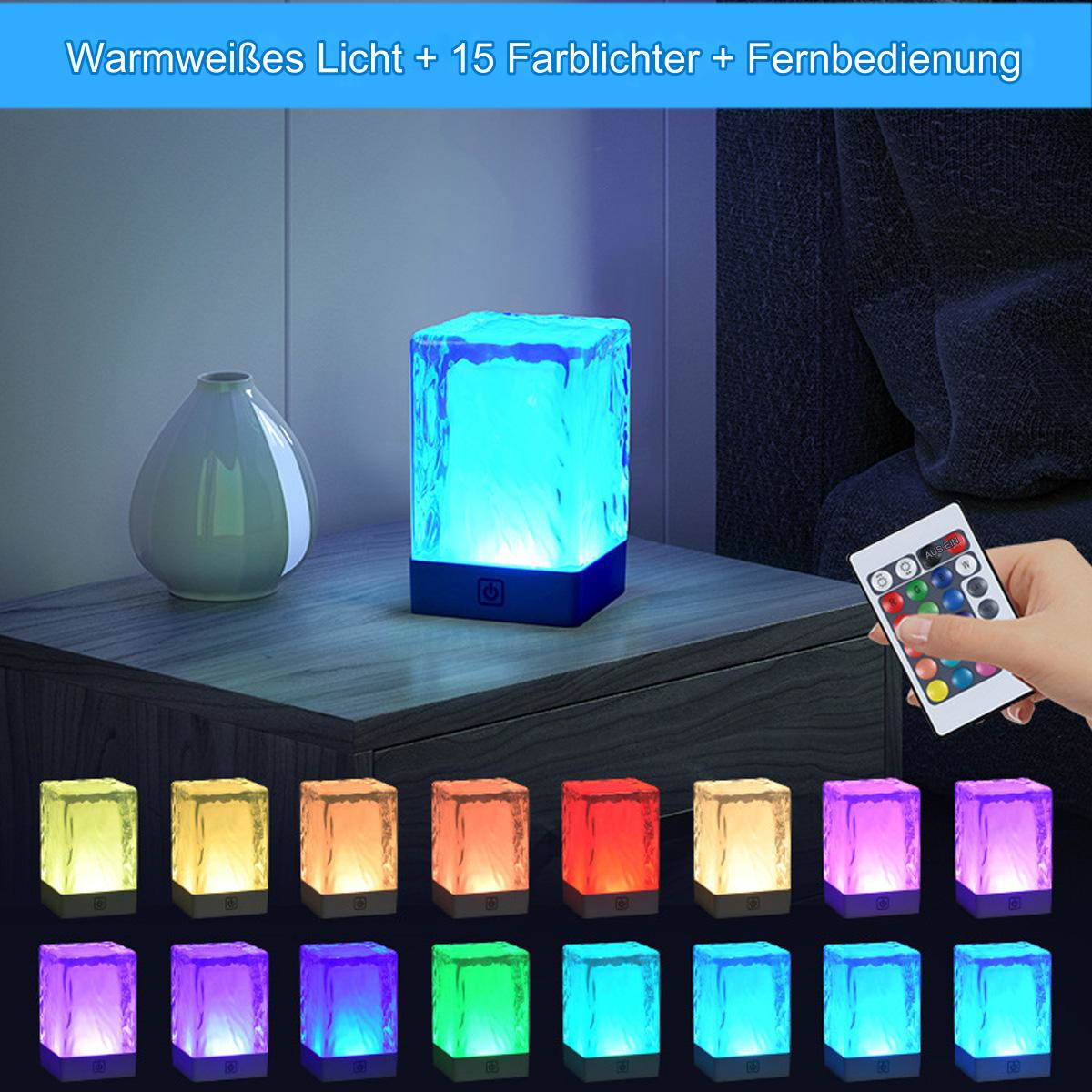 Eine würfelförmige Lampe mit mehreren Farben. Eine Fernbedienung ist sichtbar. Die Lampe steht auf einem Tisch.