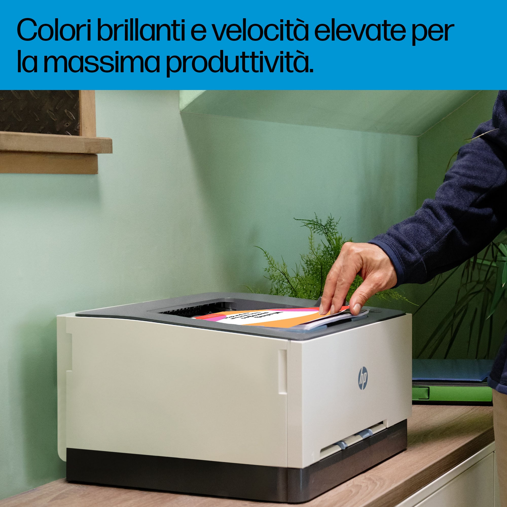 Osoba bierze wydrukowaną kartkę z białej drukarki. Drukarka stoi na drewnianym stole, tło zielonej ściany.