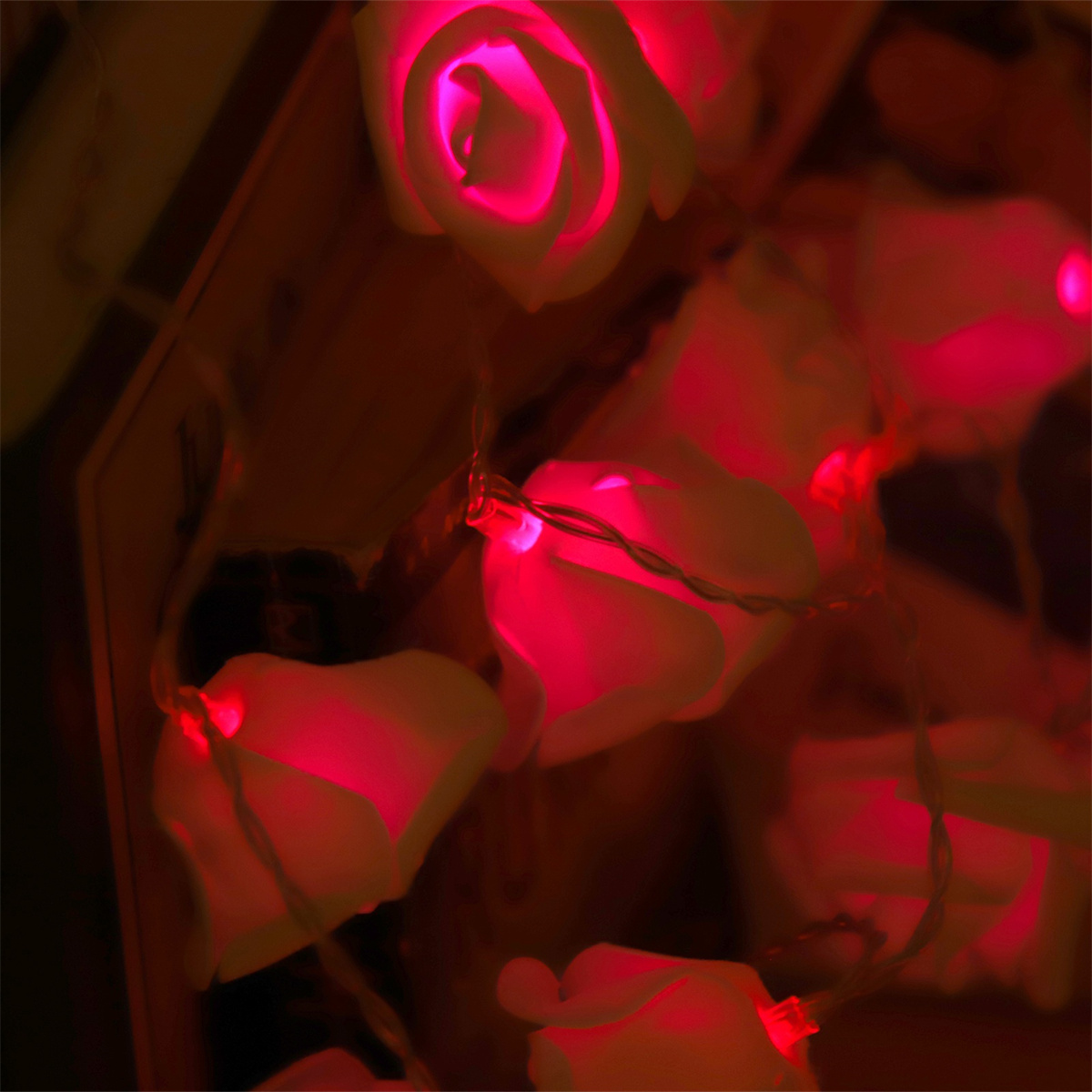 Nahaufnahme von beleuchteten weißen rosenförmigen Lichtern. Rotes Licht scheint in den Rosen und erzeugt ein warmes Leuchten.