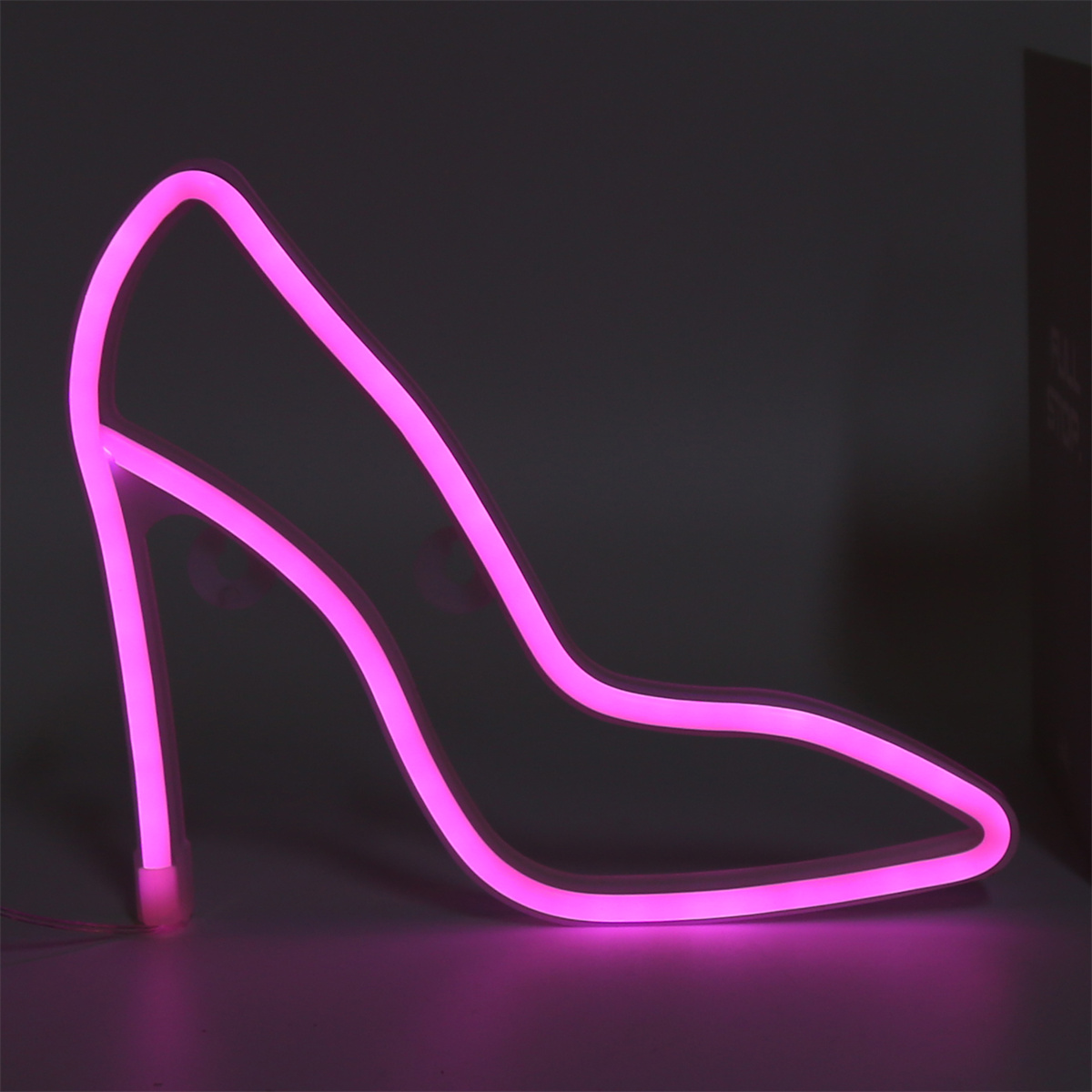 Pinke Neon-High-Heel-Schuh-Umrisse auf dunklem Hintergrund. Der Absatz ist deutlich.