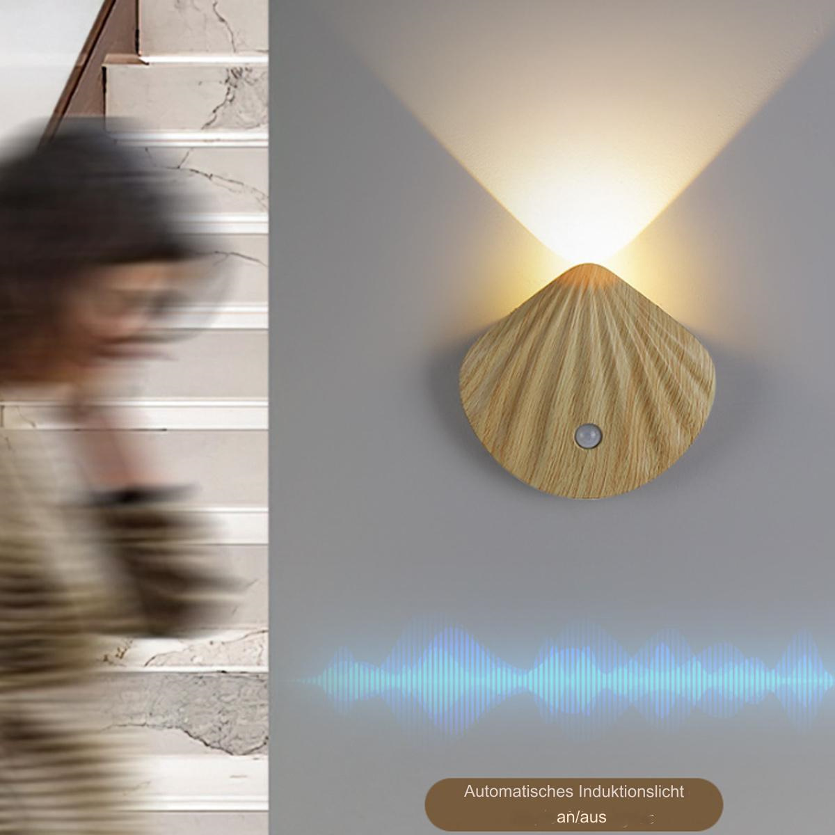 Eine Wandleuchte mit Holzschalendesign, im Hintergrund eine Person beim Gehen.