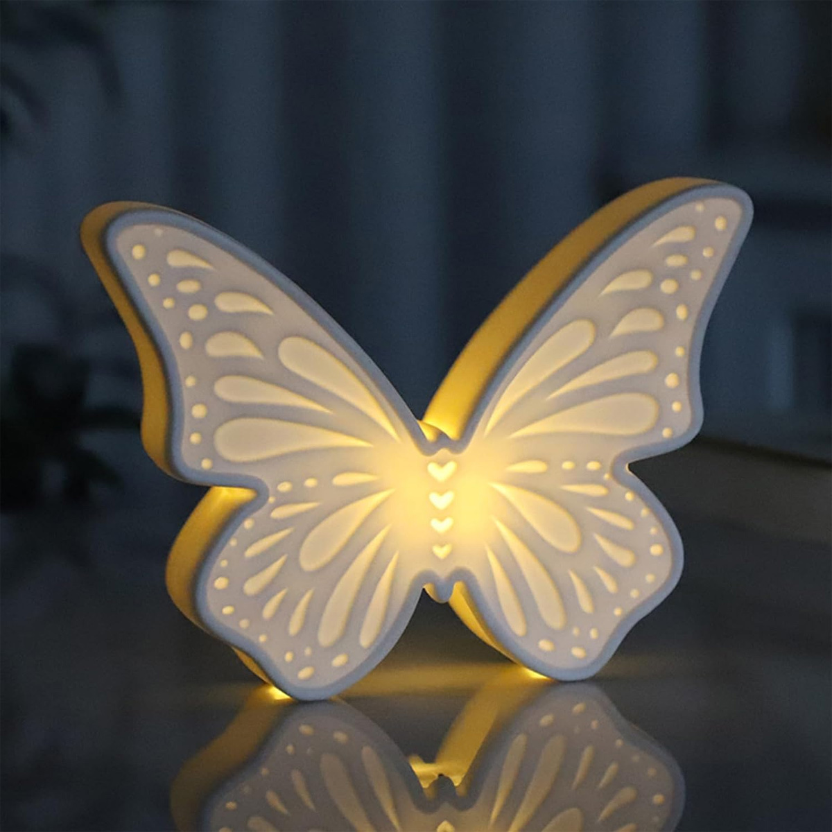 Ein leuchtendes schmetterlingsförmiges Nachtlicht mit warmem, einladendem Glanz. Reflektiert auf der Oberfläche.