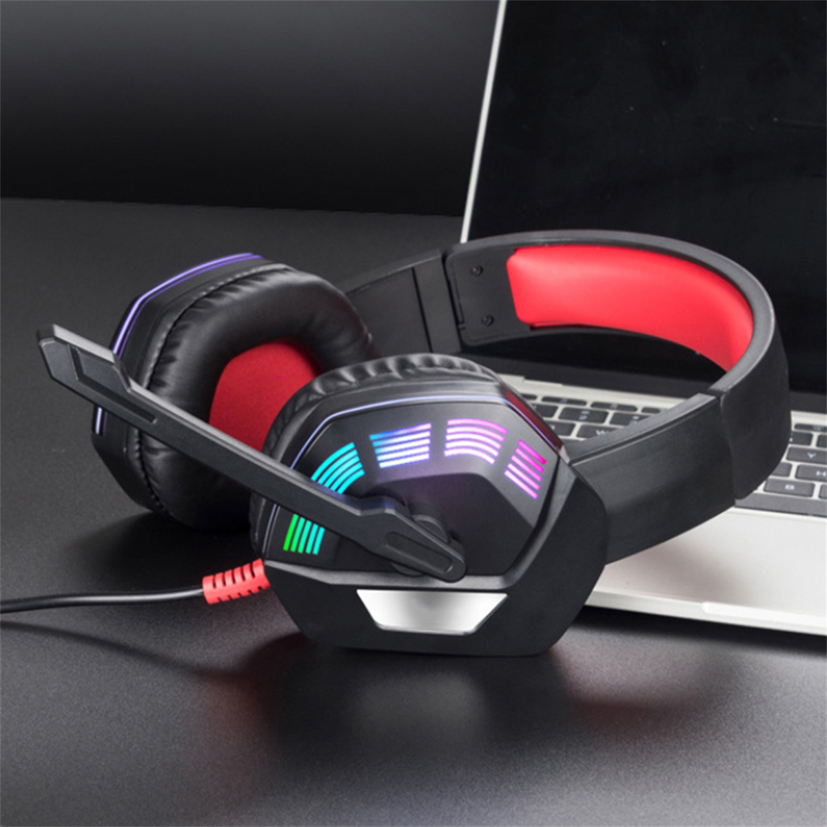 Schwarzes Gaming-Headset mit roten Ohrmuscheln, an einen Laptop angeschlossen.