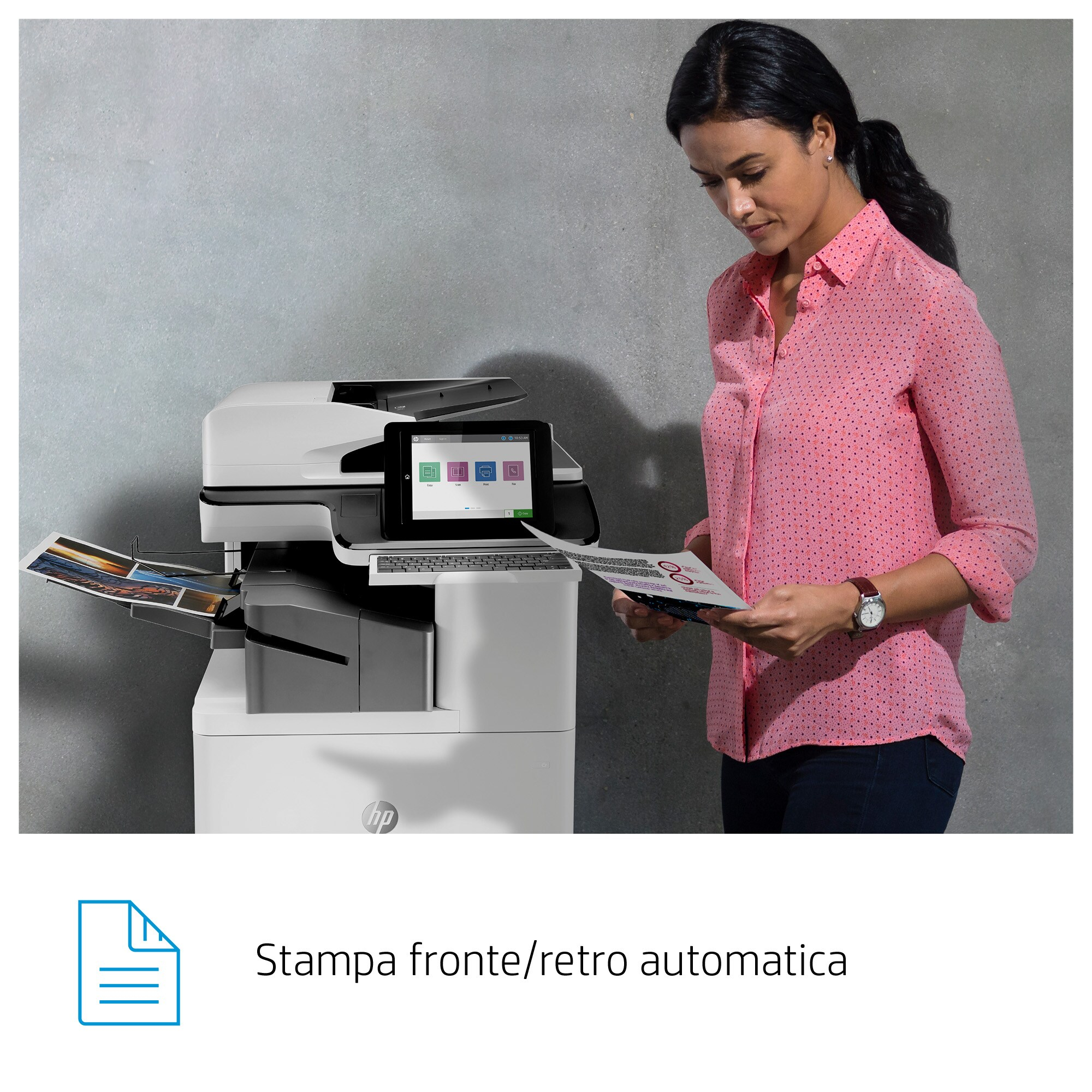 Una donna guarda un foglio vicino a una stampante bianca.