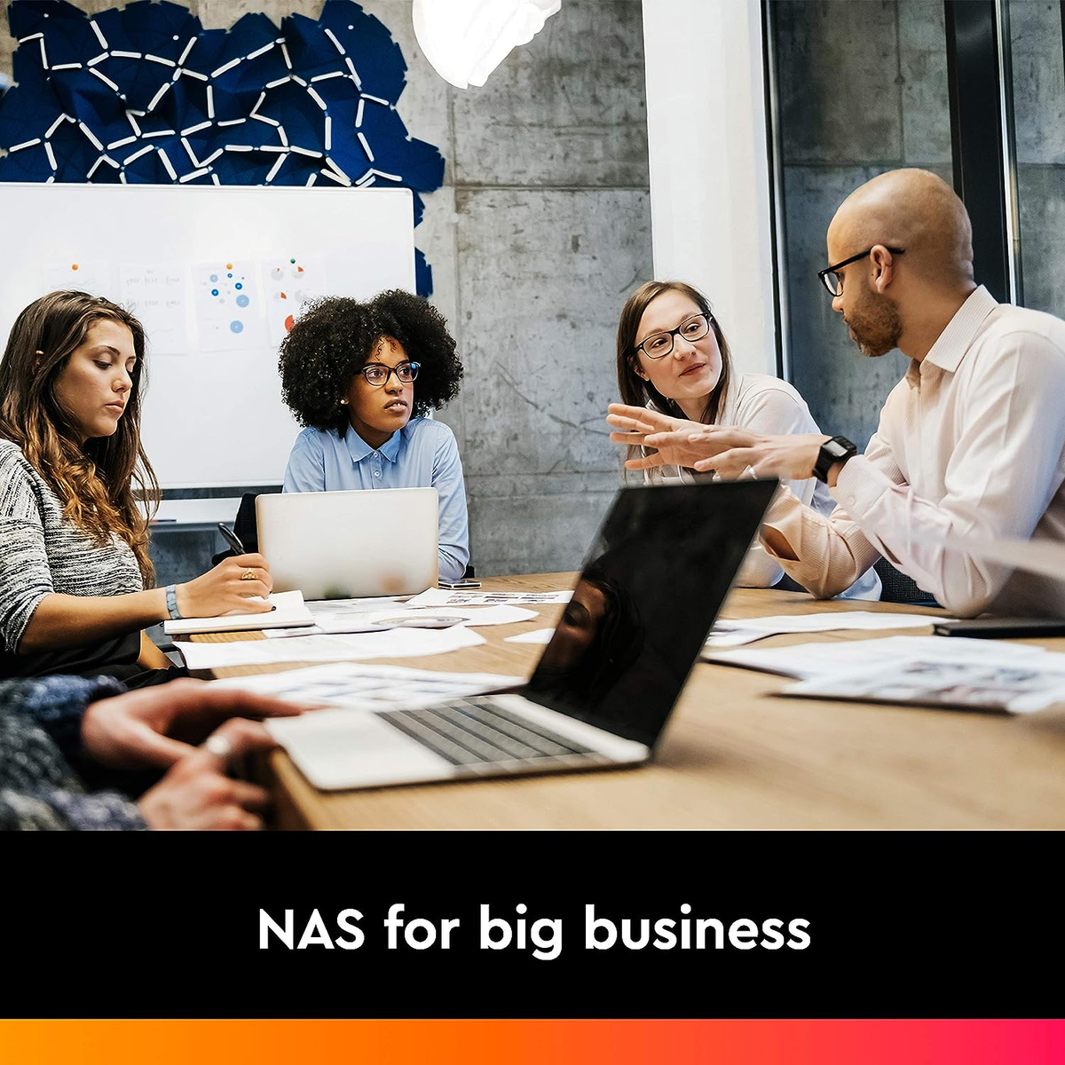 Spotkanie biznesowe z czterema osobami wokół stołu, z laptopem w centrum.