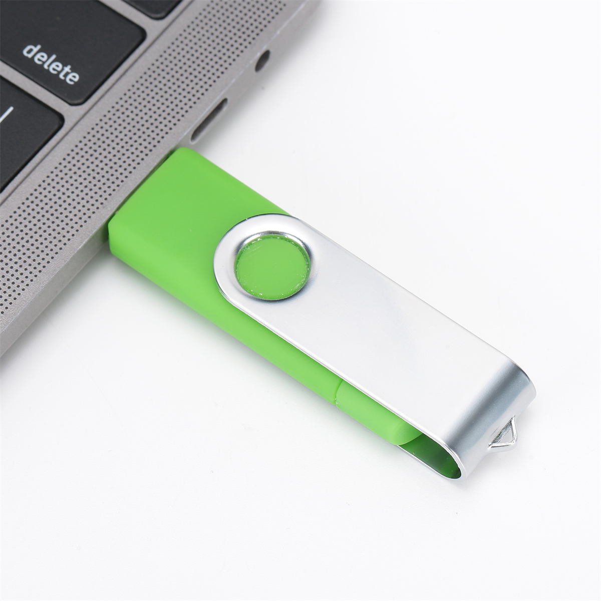Ein grüner USB-Stick wird in einen Laptop gesteckt. Das Laufwerk ist silber und grün.