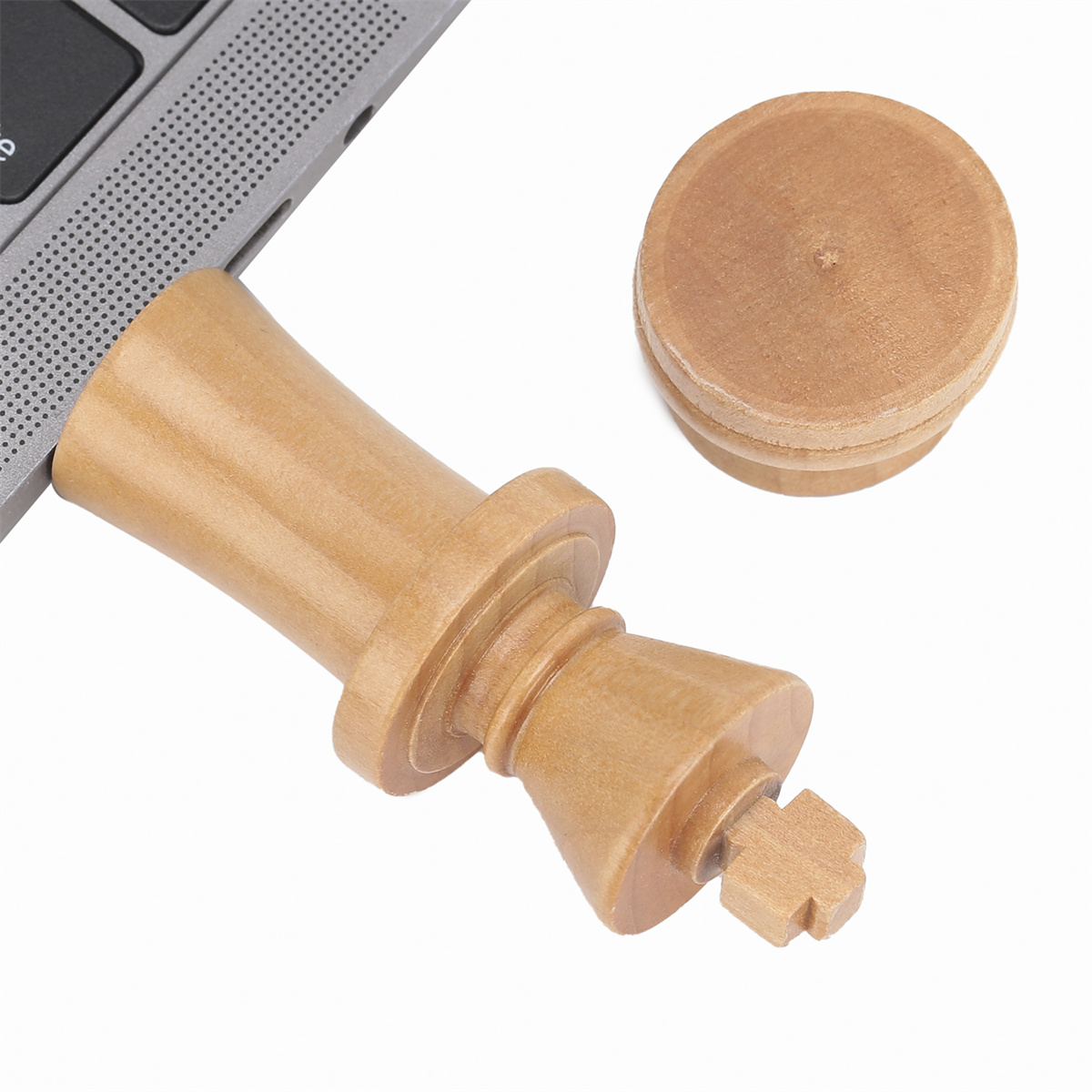 Hölzerner Schachkönig USB-Stick, der an einen Laptop angeschlossen ist. Ein weiteres Königsteil daneben.