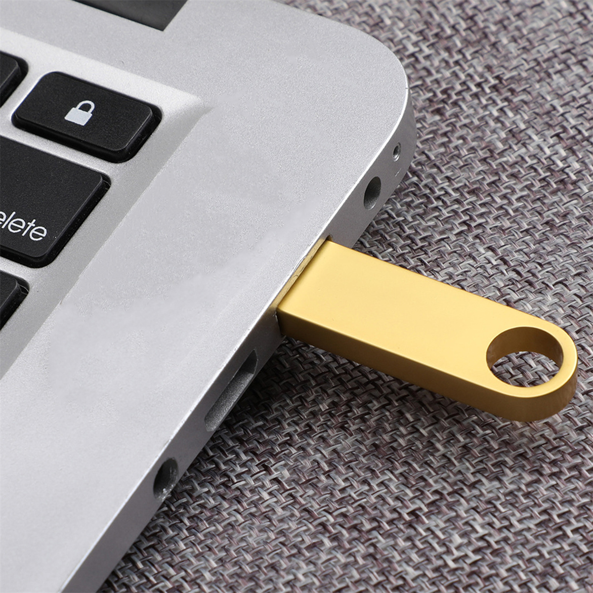 Ein goldener USB-Stick ist in die Seite eines silbernen Laptops gesteckt.