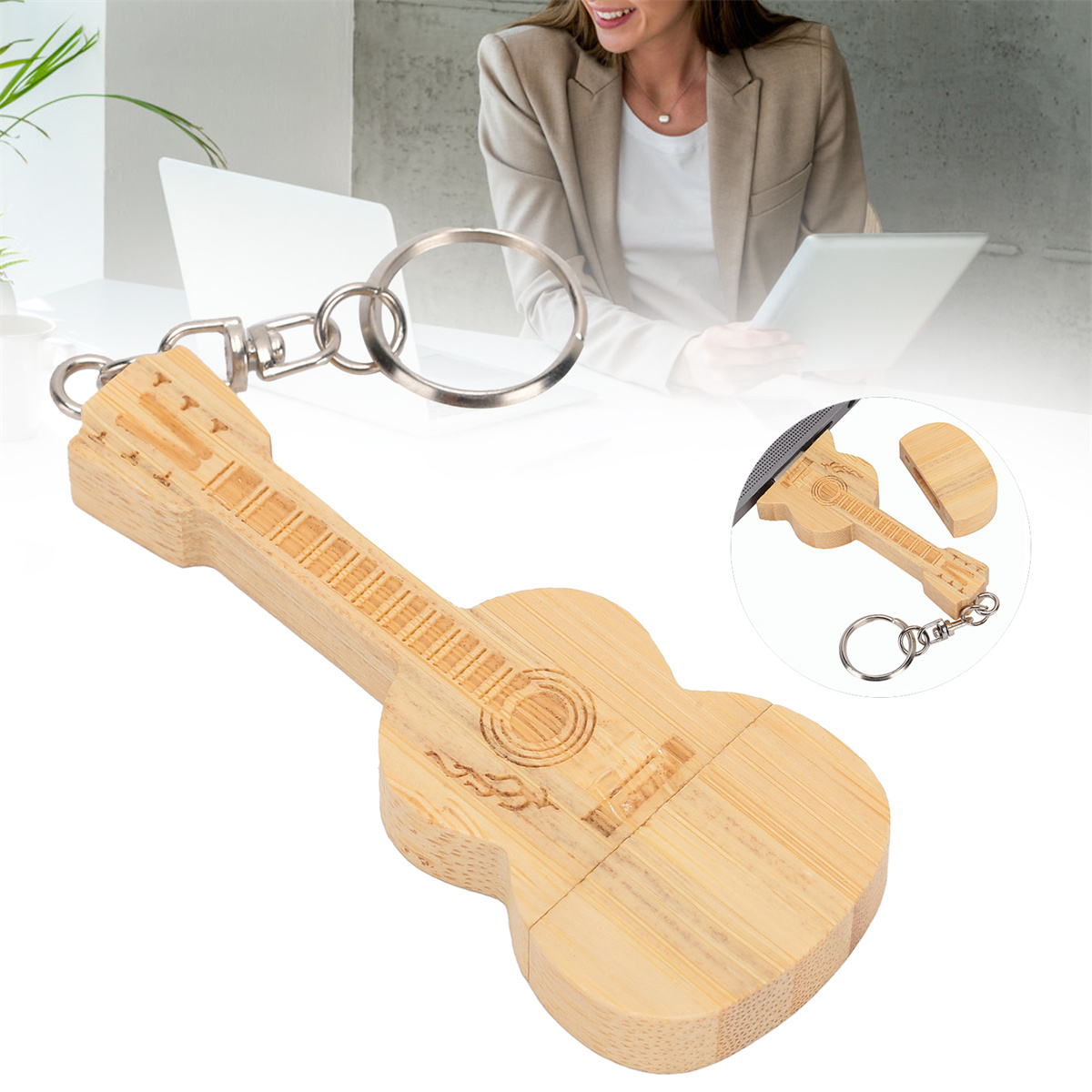 Gitarrenförmiger Schlüsselanhänger aus Holz mit silberner Kette. Im Hintergrund eine Frau und ein Laptop.