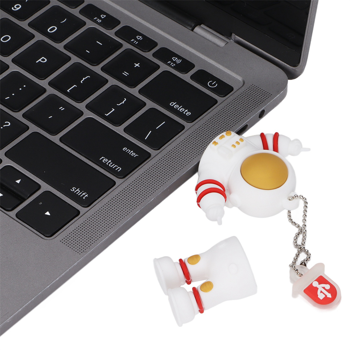 Astronaut-USB-Stick und passende Schlüsselanhänger neben einer Laptop-Tastatur.