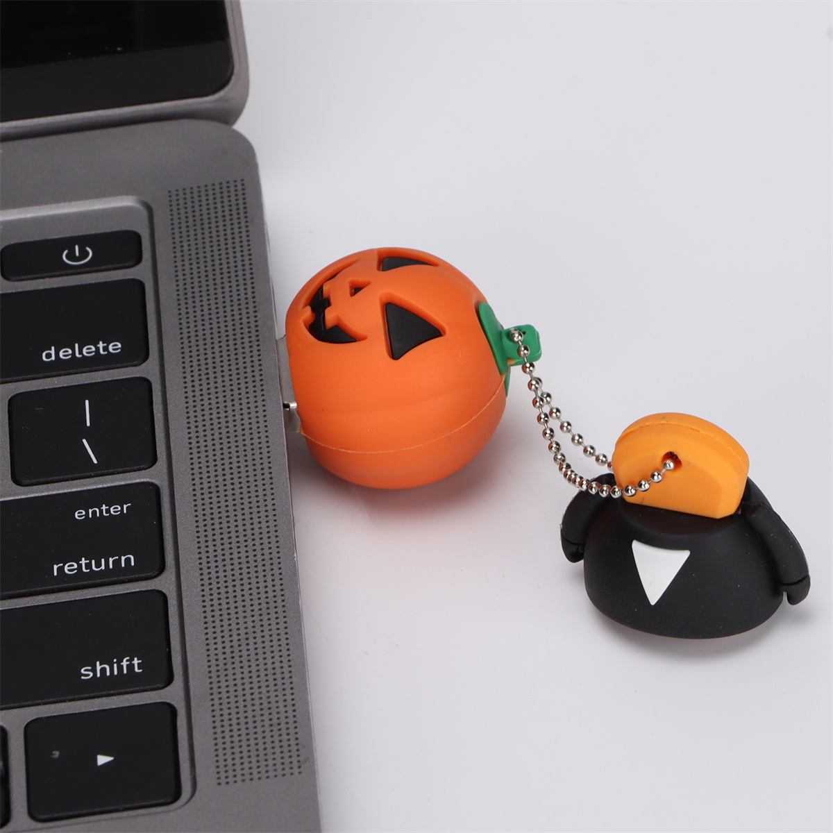 Kürbisförmiger USB-Stick, der an einen Laptop angeschlossen ist. Weiße Oberfläche.